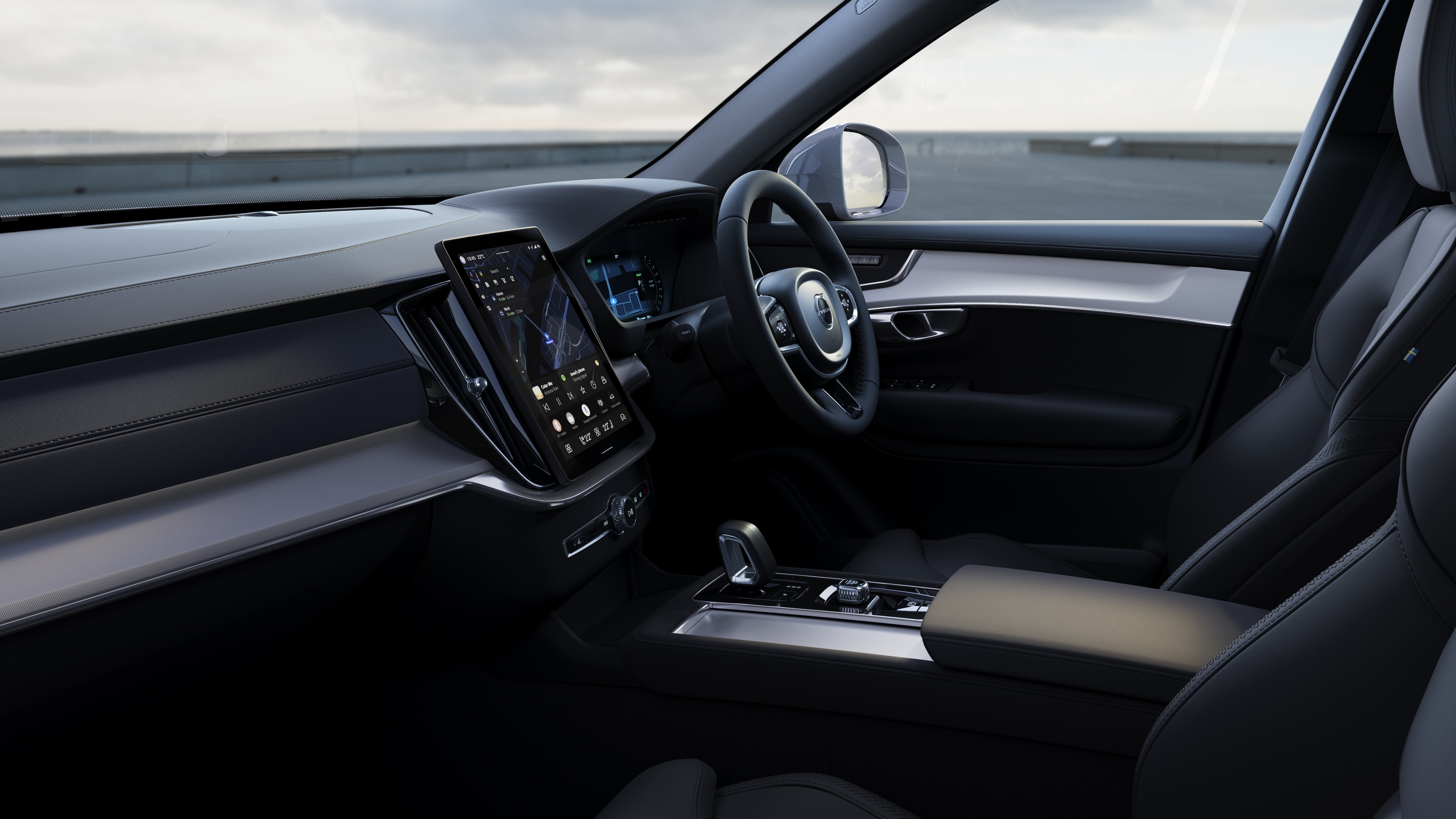 Volvo car interior showing dashboard, steering wheel, and center console with digital display in an open road background.