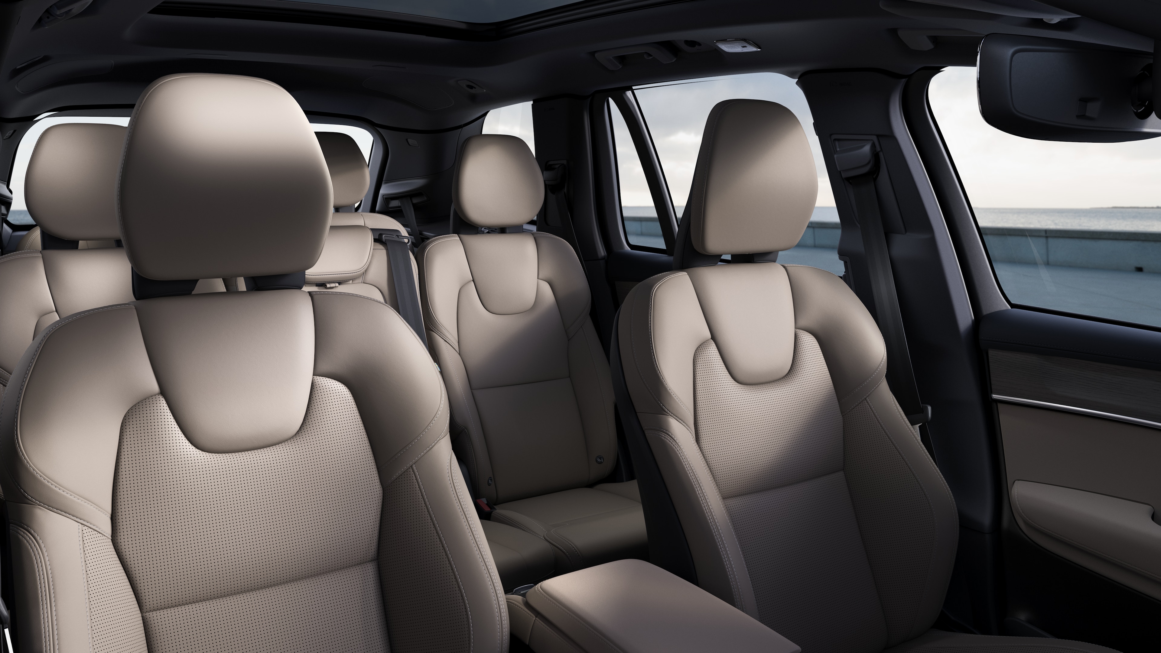 Volvo car interior showing front and rear passenger seats, steering wheel, dashboard, and center console against a plain studio background.