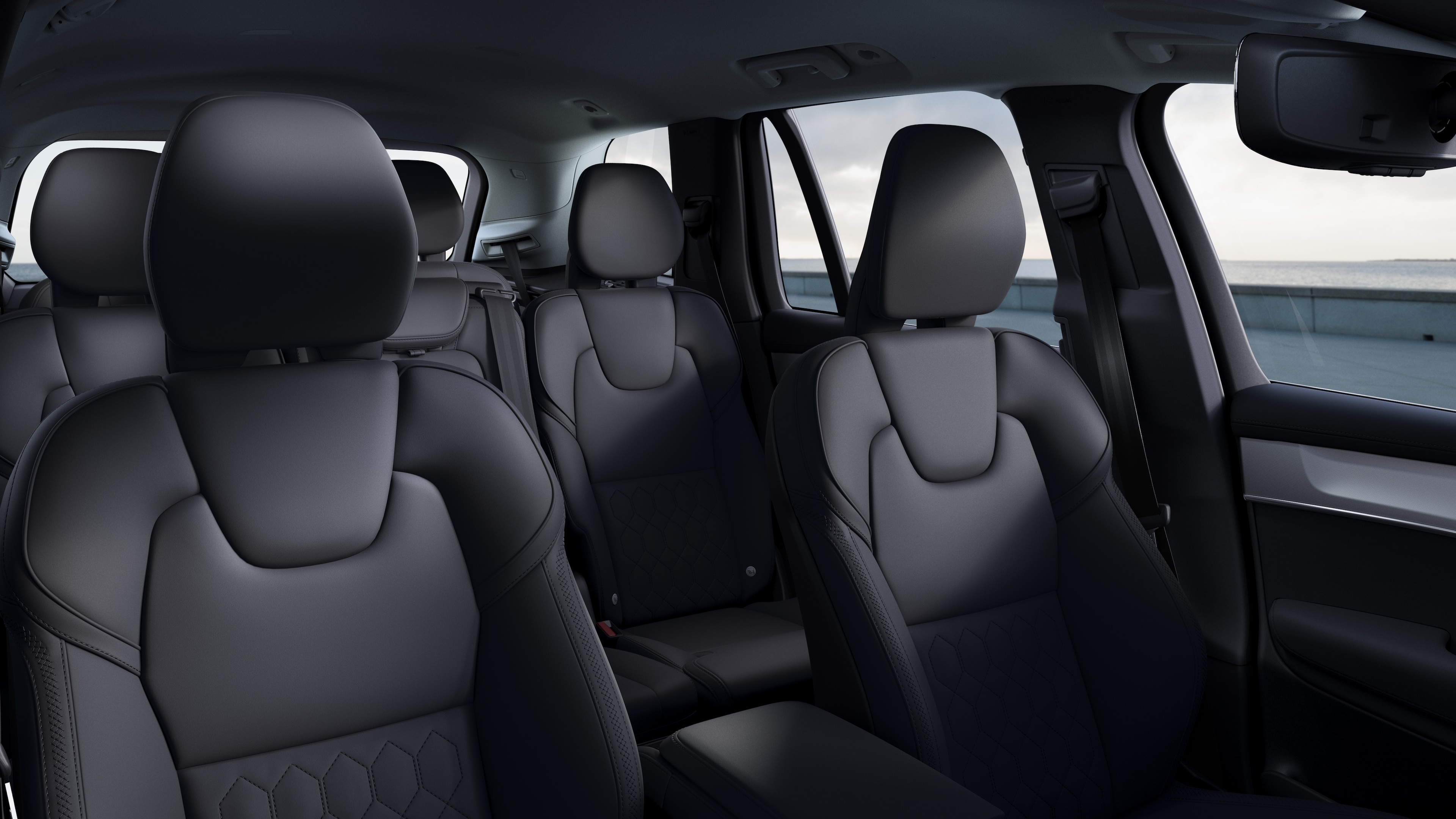 Volvo -auton sisätiloissa näkyy etu- ja takamatkustajan istuimet, ohjauspyörä, kojelauta ja keskikonsoli selkeällä studiotaustalla.