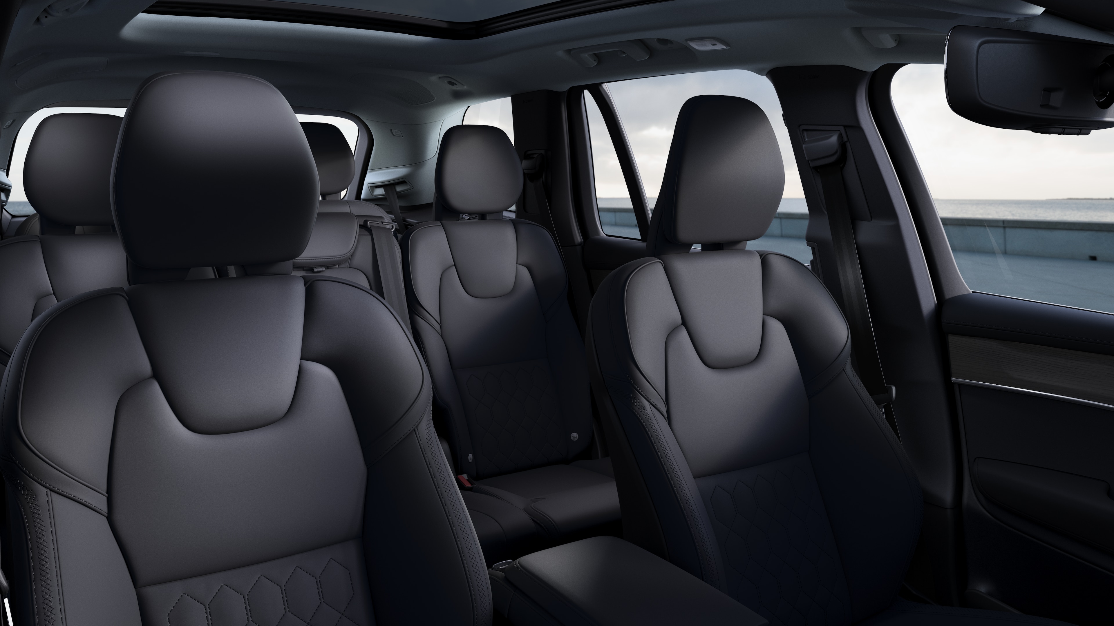 Volvo car interior showing front and rear passenger seats, steering wheel, dashboard, and center console against a plain studio background.