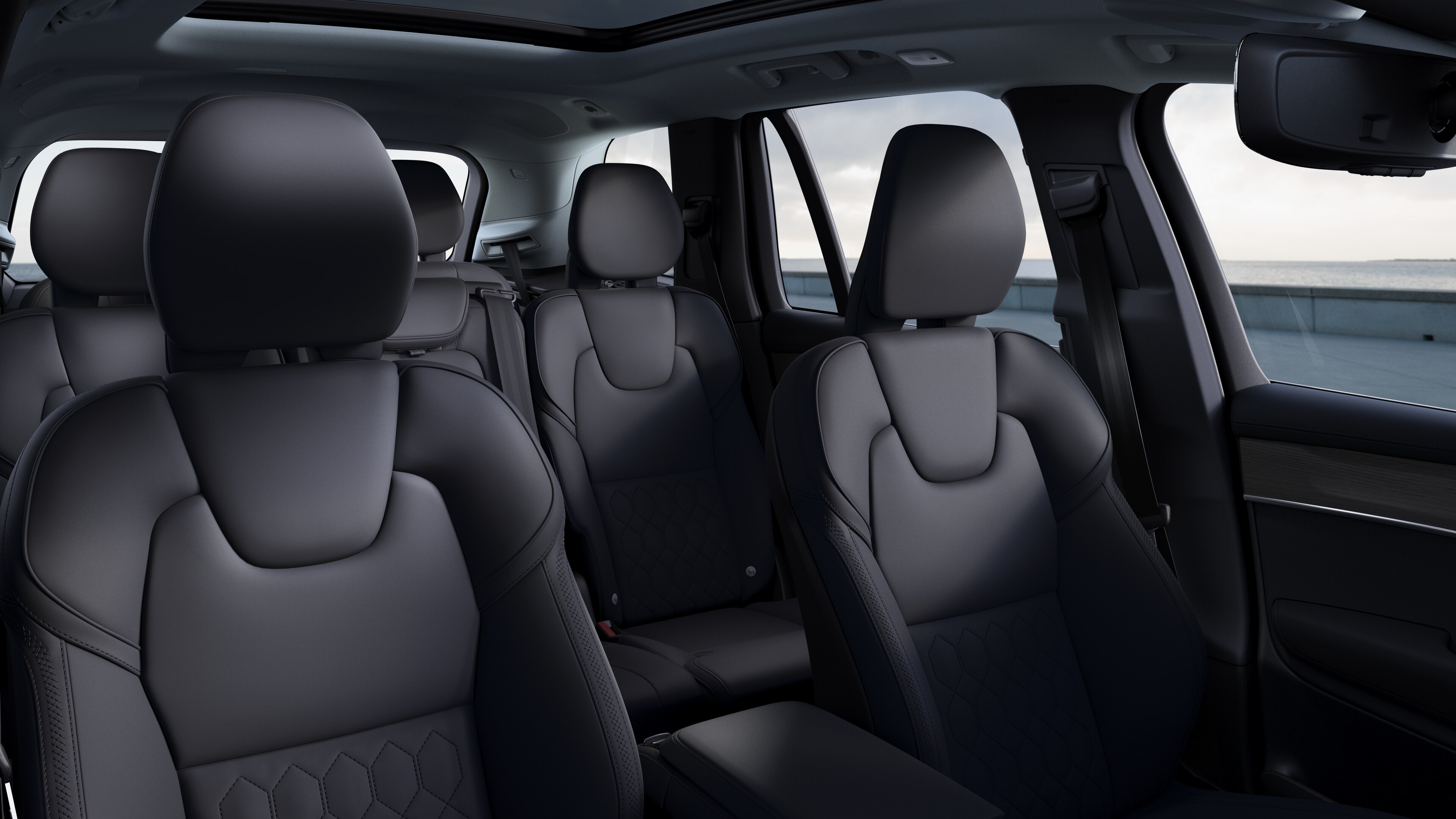 Volvo car interior showing front and rear passenger seats, steering wheel, dashboard, and center console against a plain studio background.