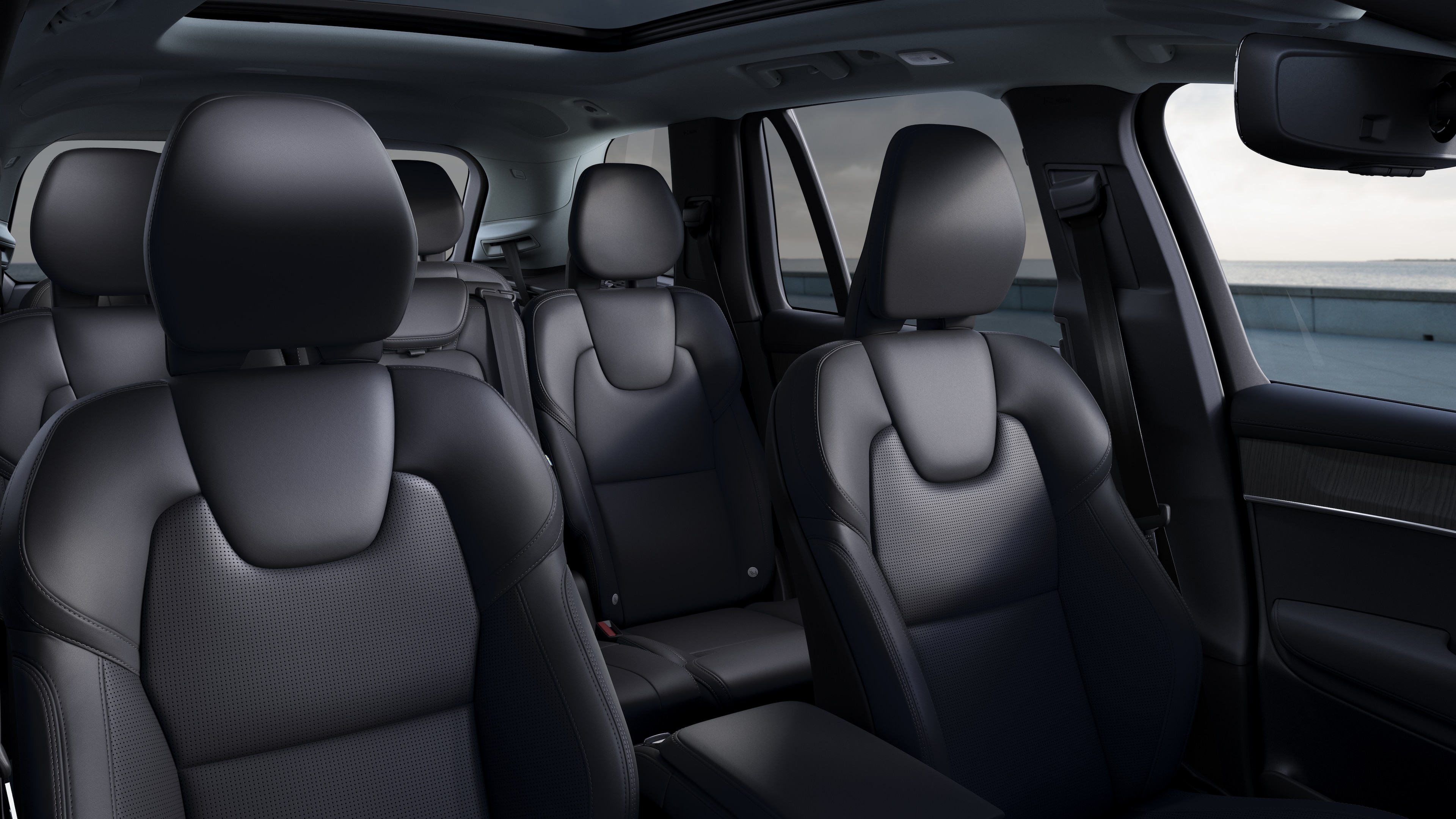 Volvo car interior showing front and rear passenger seats, steering wheel, dashboard, and center console against a plain studio background.