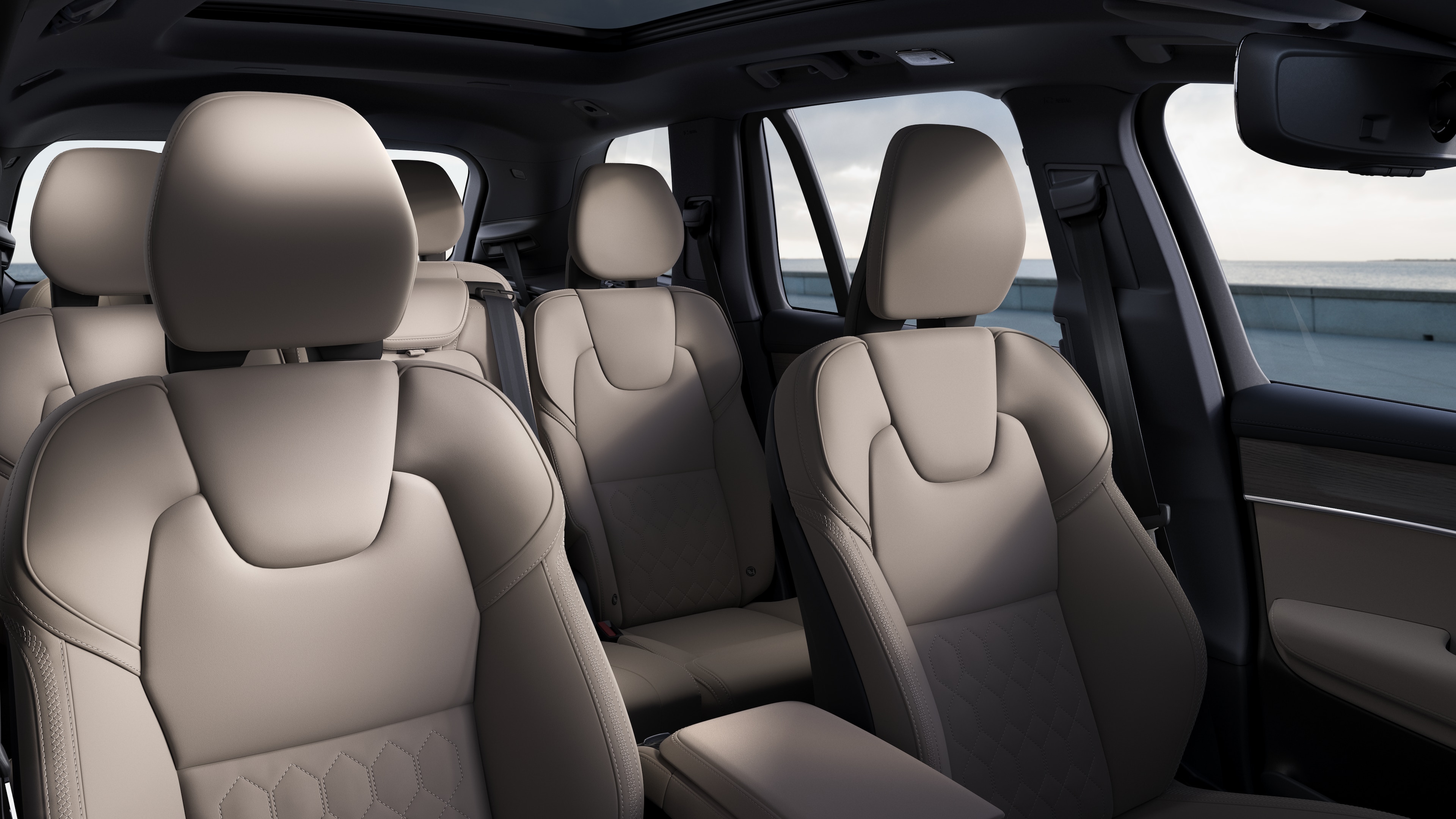 평범한 스튜디오 배경에 앞좌석 및 뒷좌석 조수석, 스티어링 휠, 대시보드 및 센터 콘솔을 보여주는 볼보 자동차 내부.