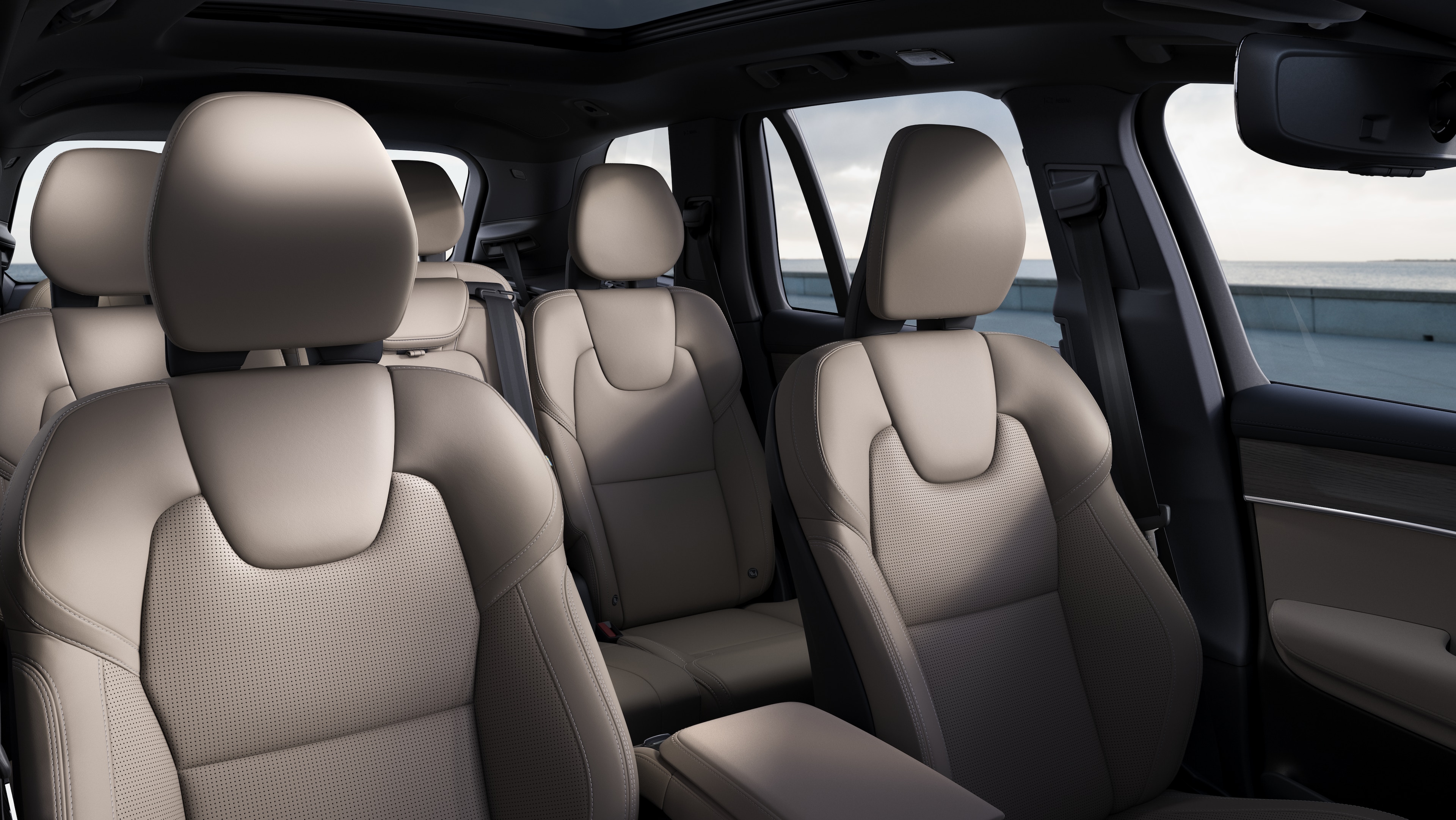 평범한 스튜디오 배경에 앞좌석 및 뒷좌석 조수석, 스티어링 휠, 대시보드 및 센터 콘솔을 보여주는 볼보 자동차 내부.