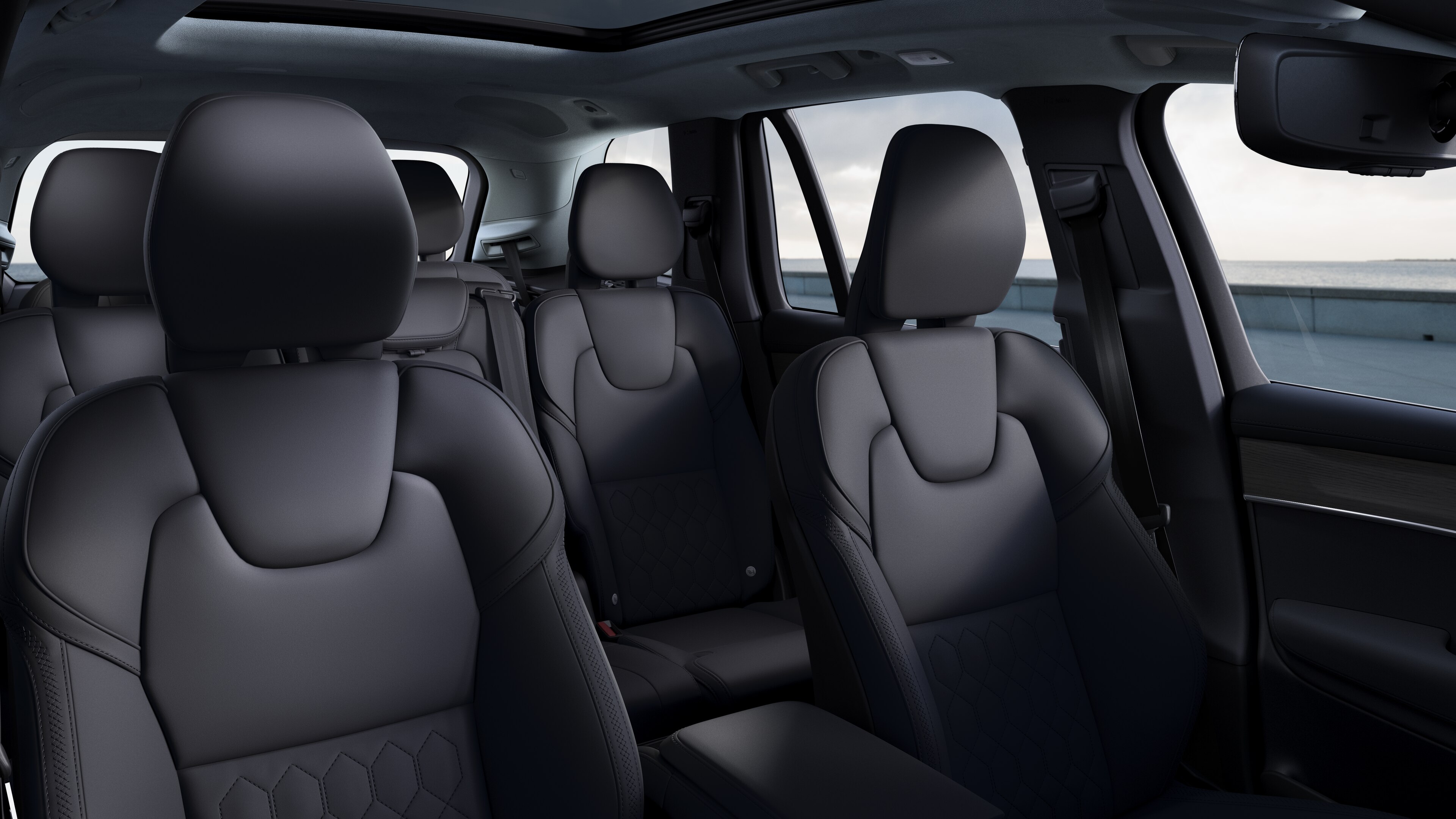 Volvo car interior showing front and rear passenger seats, steering wheel, dashboard, and center console against a plain studio background.