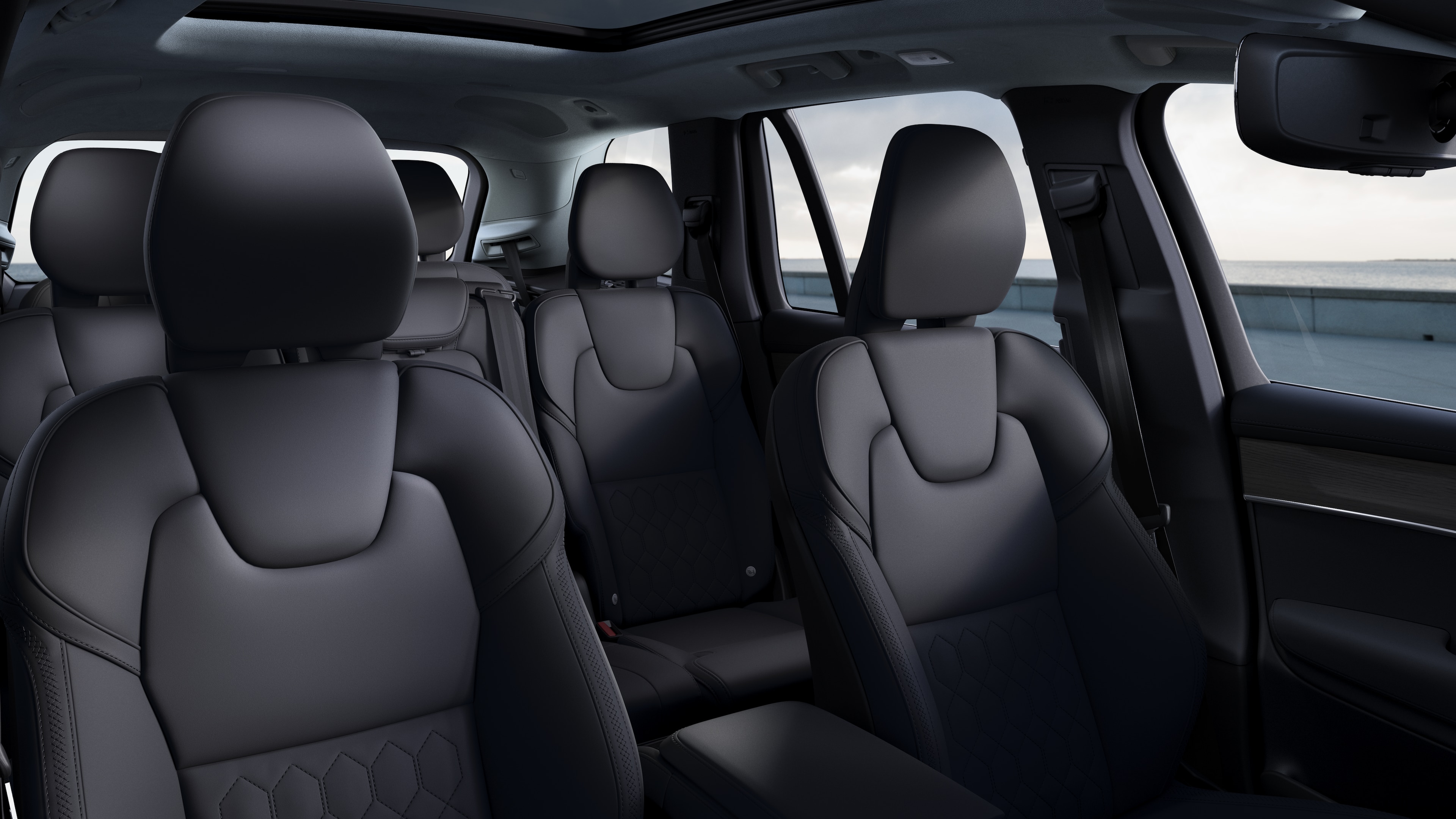 Volvo car interior showing front and rear passenger seats, steering wheel, dashboard, and center console against a plain studio background.