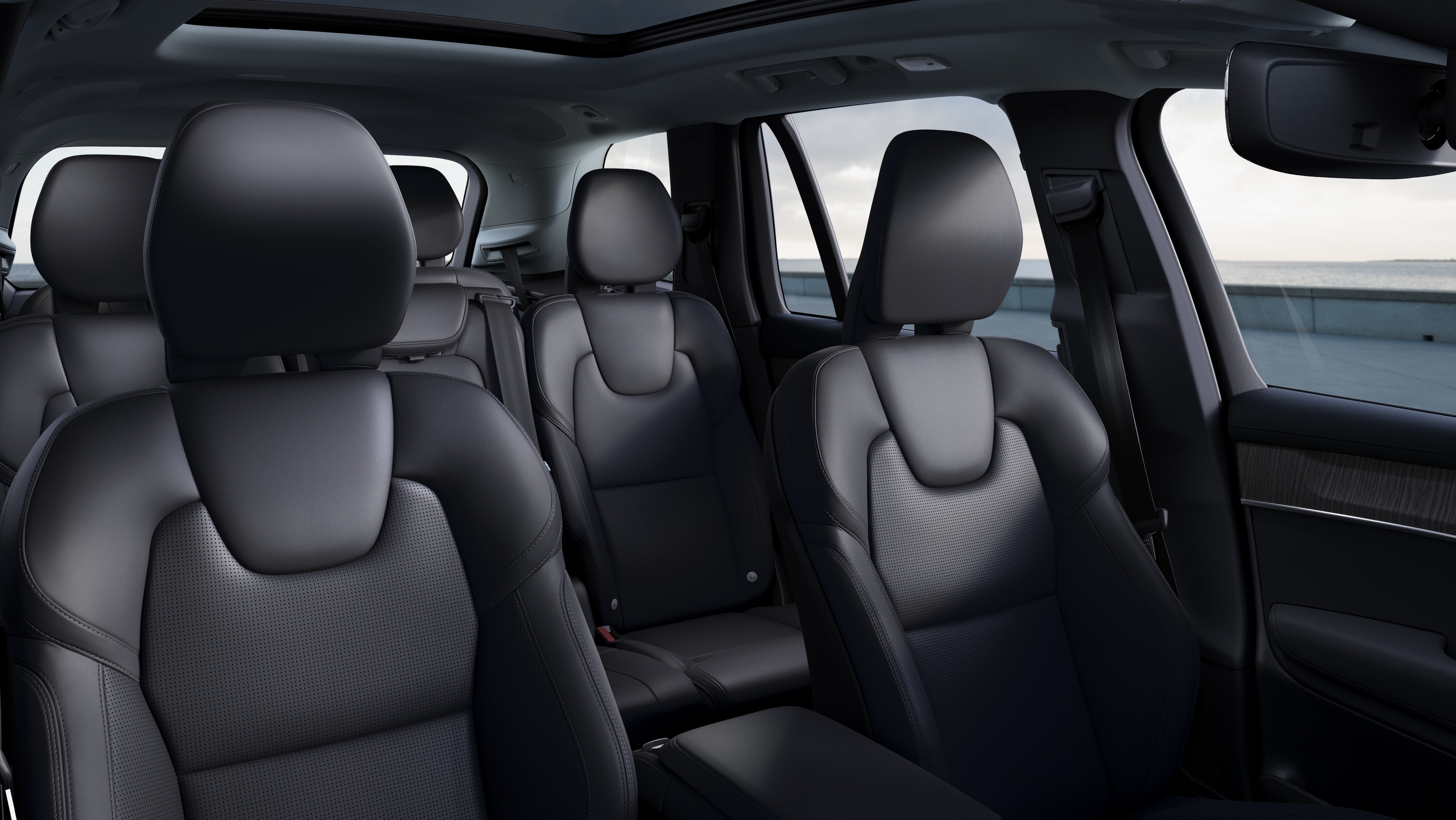 Volvo car interior showing front and rear passenger seats, steering wheel, dashboard, and center console against a plain studio background.