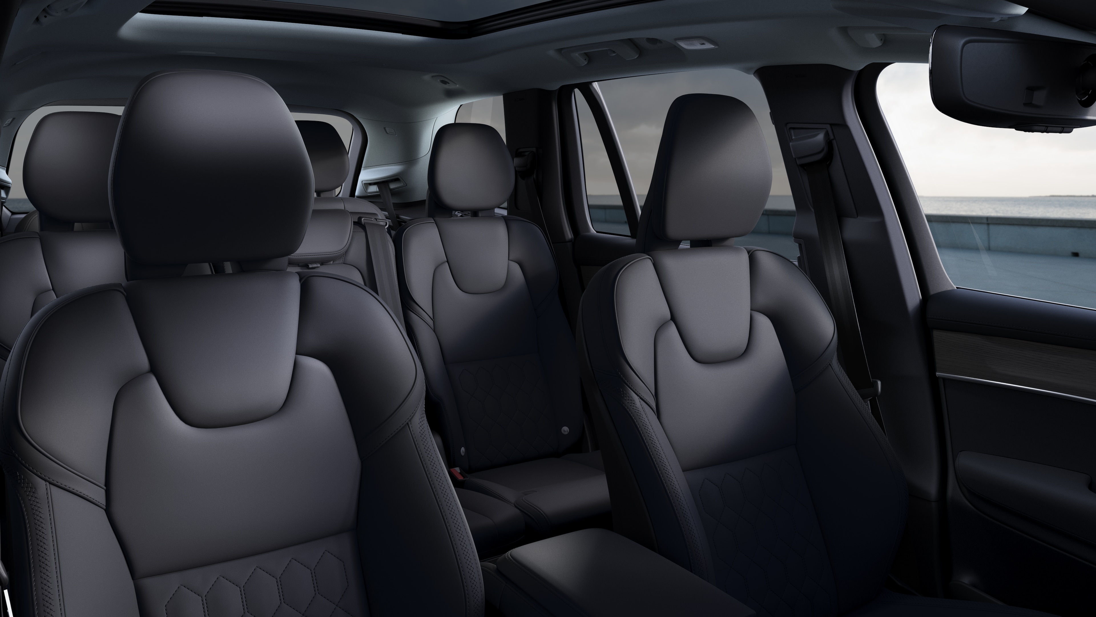 Volvo car interior showing front and rear passenger seats, steering wheel, dashboard, and center console against a plain studio background.