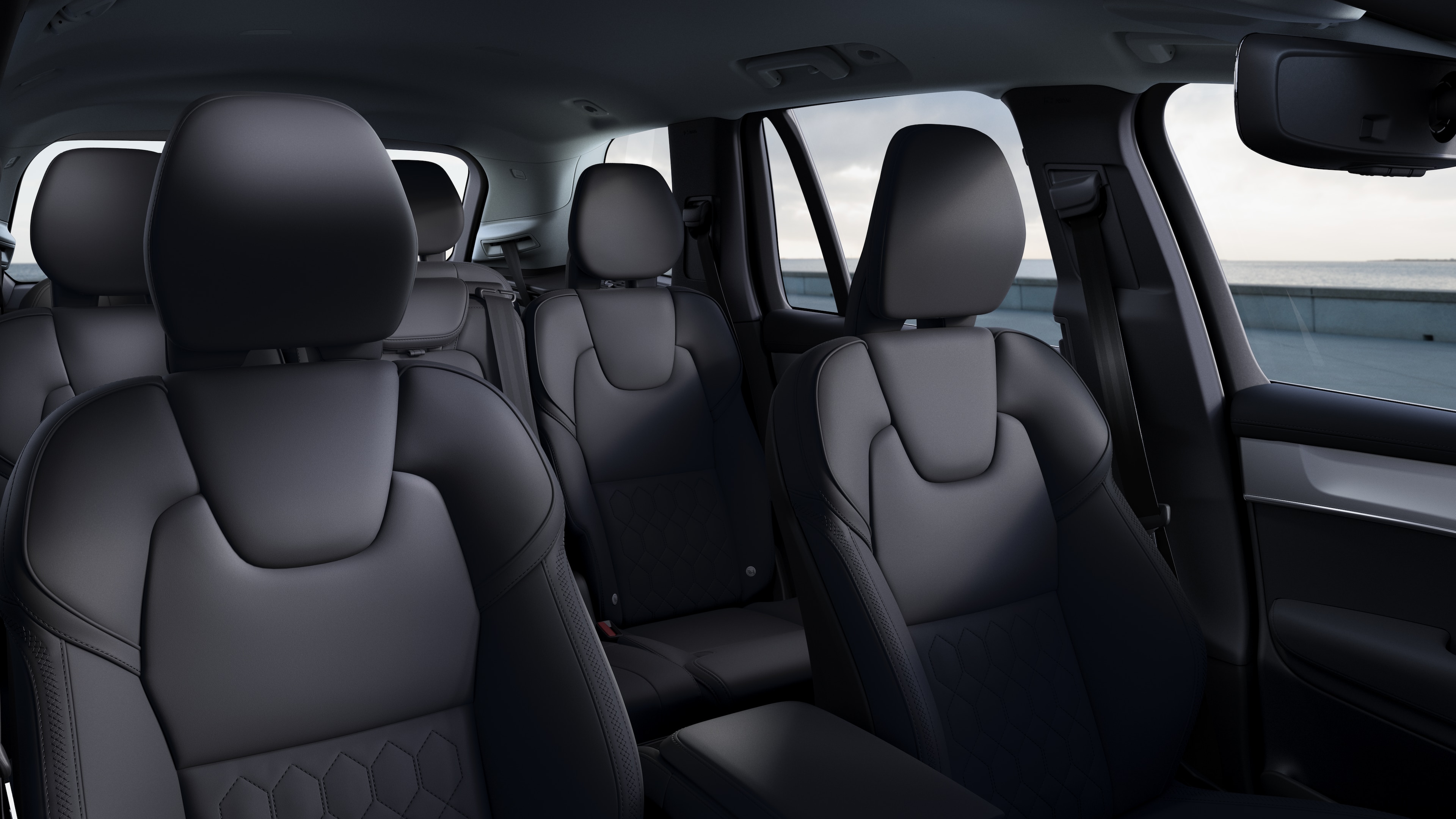 Wnętrze samochodu Volvo z przednimi i tylnymi siedzeniami pasażerów, kierownicą, deską rozdzielczą i konsolą środkową na tle zwykłego studia.