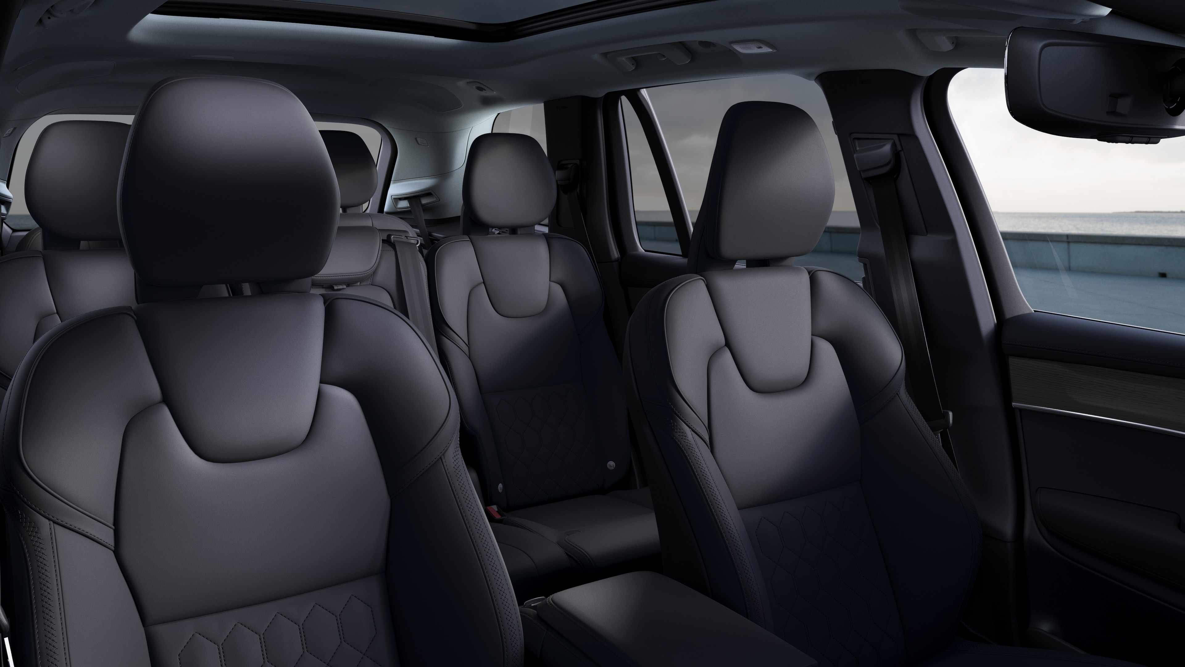 Volvo car interior showing front and rear passenger seats, steering wheel, dashboard, and center console against a plain studio background.