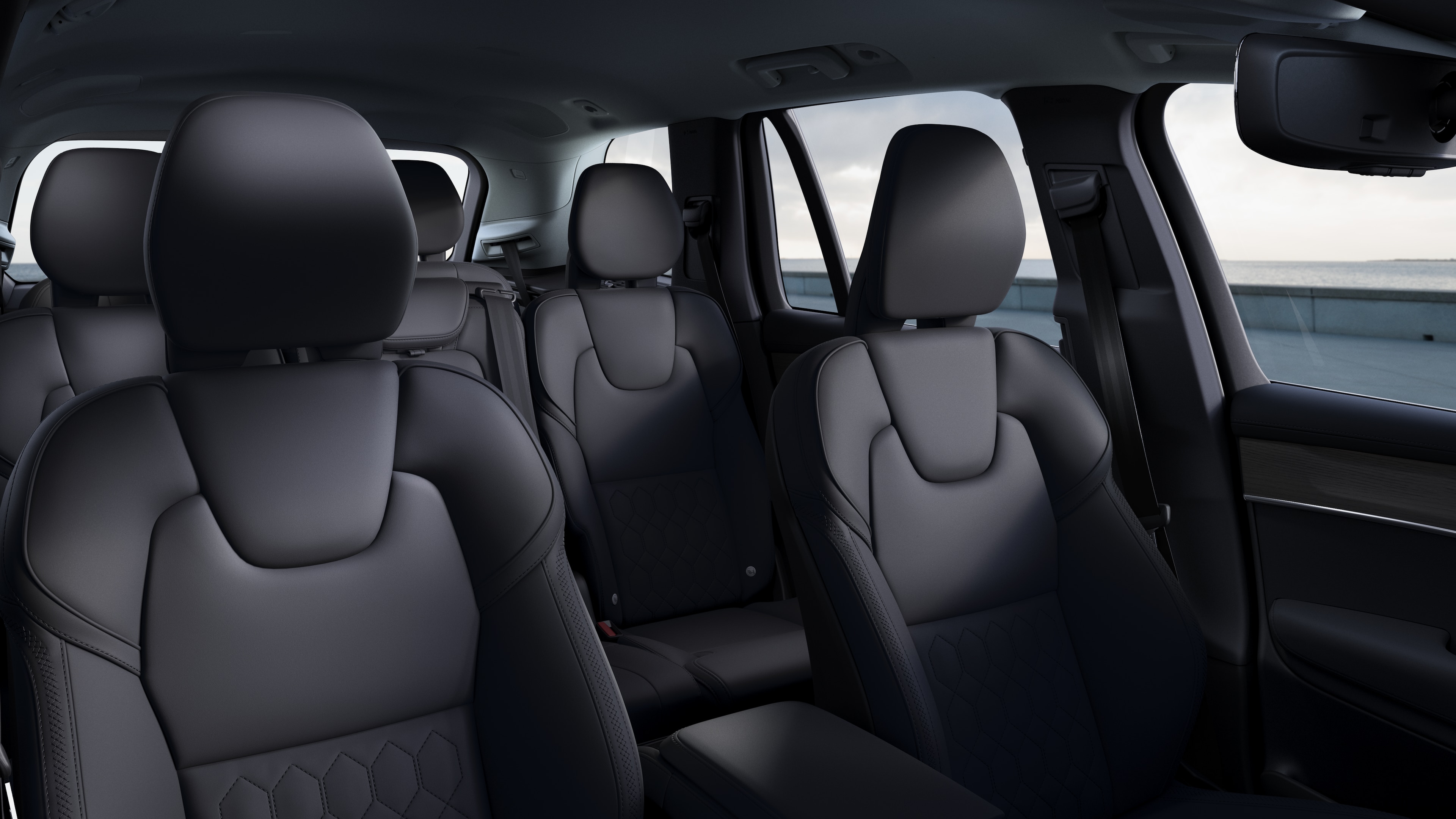 Volvo car interior showing front and rear passenger seats, steering wheel, dashboard, and center console against a plain studio background.