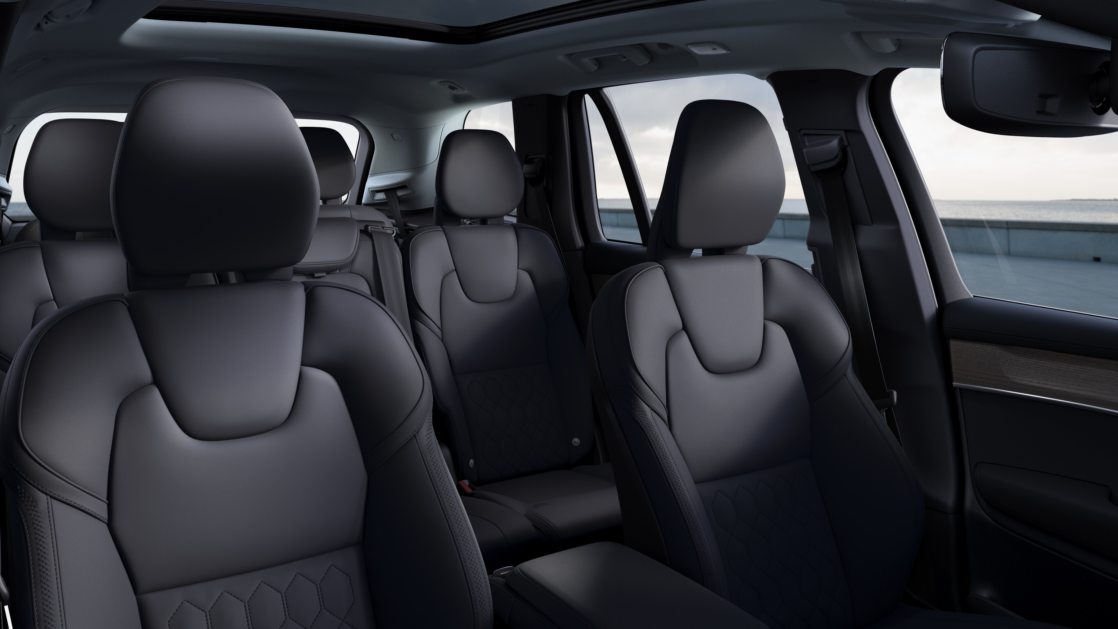 Volvo car interior showing front and rear passenger seats, steering wheel, dashboard, and center console against a plain studio background.