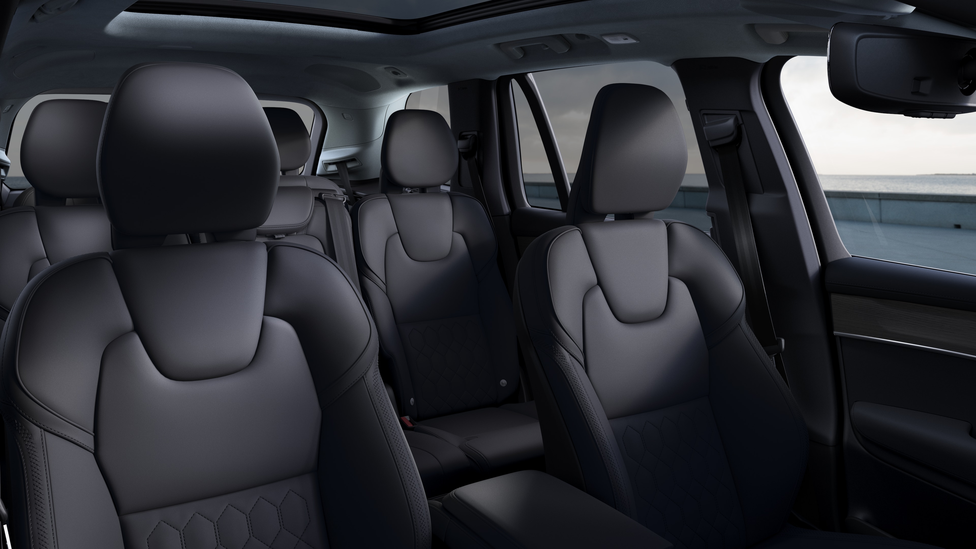 Volvo car interior showing front and rear passenger seats, steering wheel, dashboard, and center console against a plain studio background.