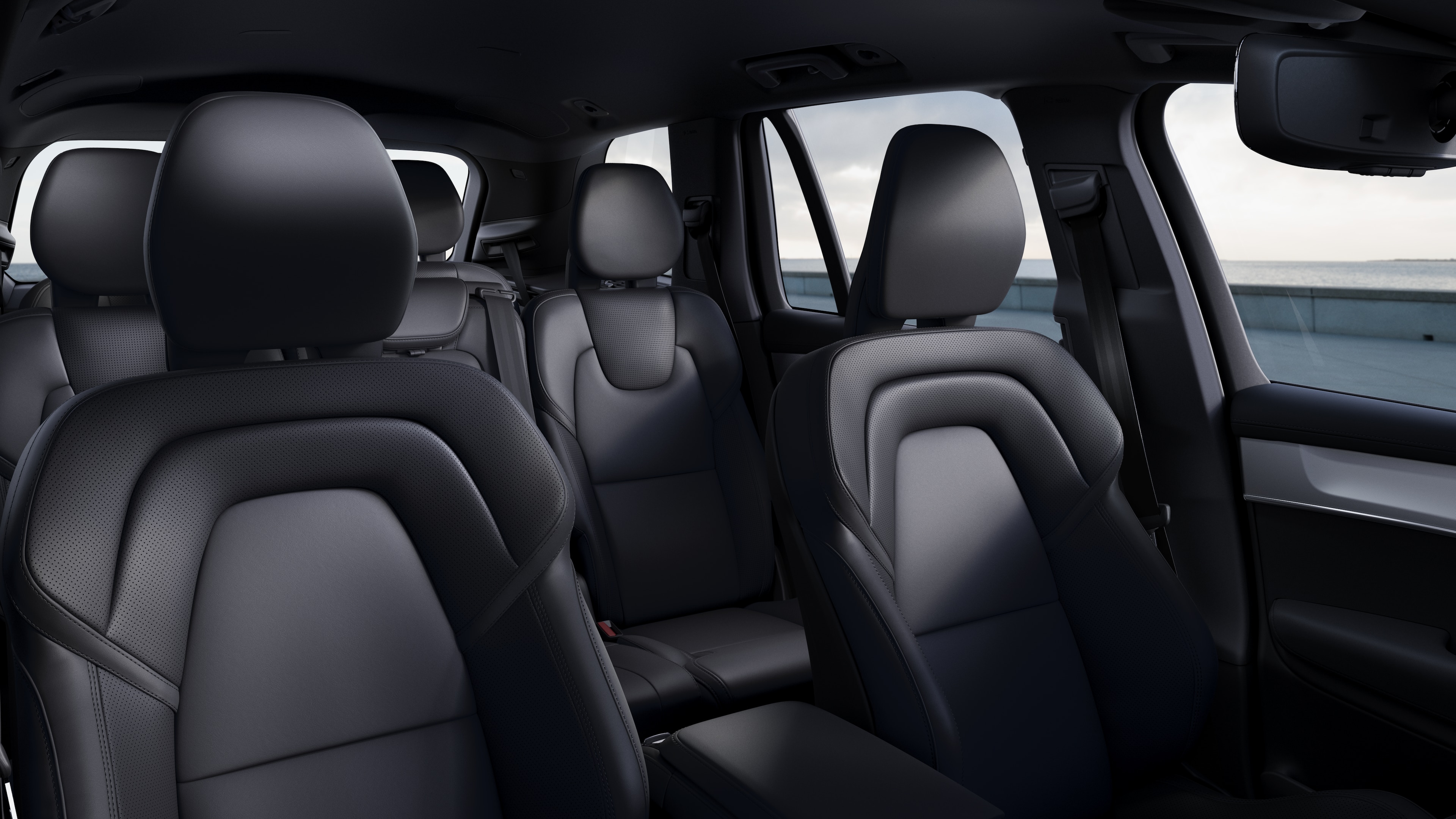 Interior de un coche Volvo que muestra los asientos del pasajero delantero y trasero, el volante, el salpicadero y la consola central sobre un fondo de estudio liso.