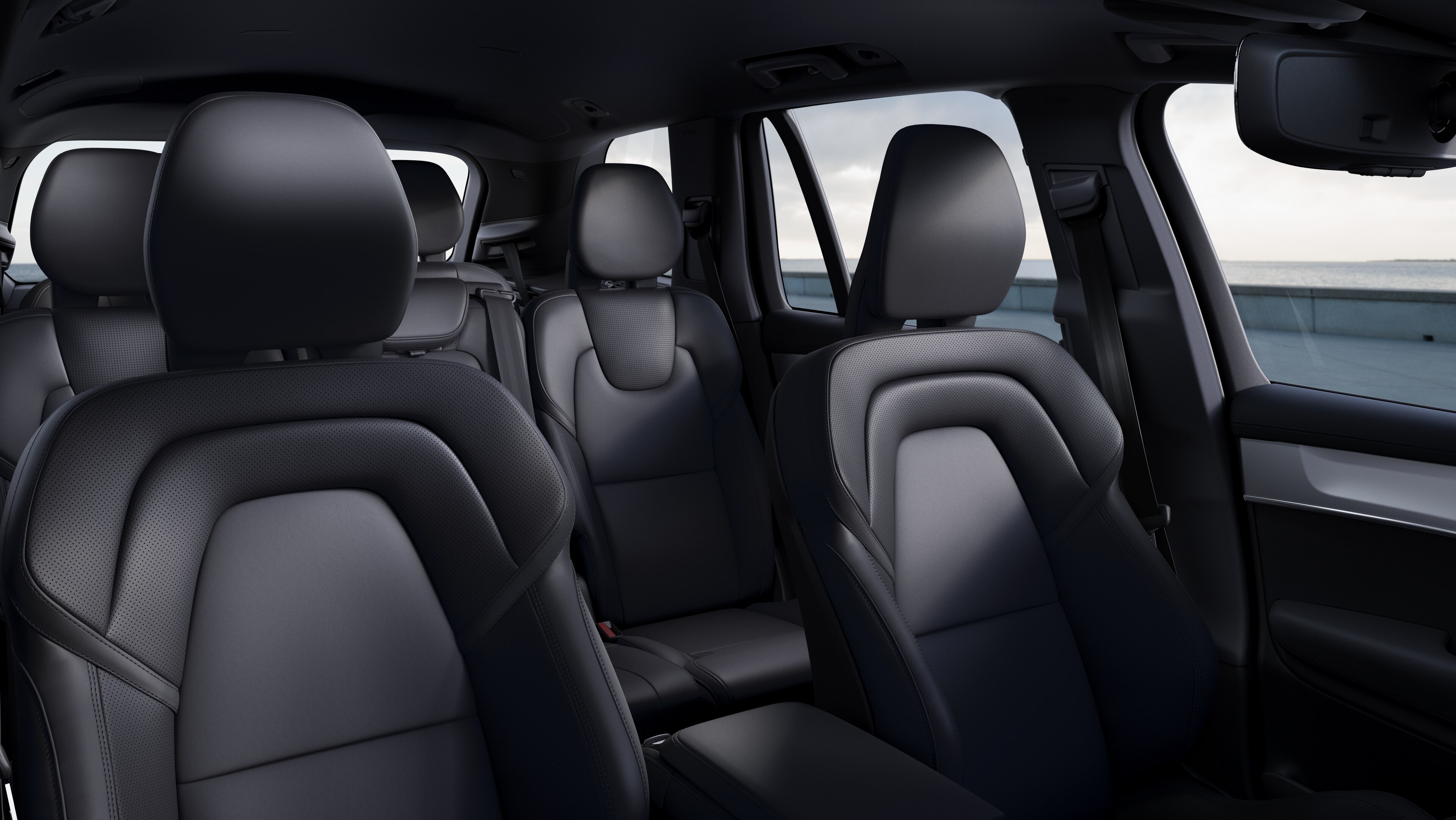 Het interieur van een Volvo met de passagiersstoelen voor- en achterin, het stuur, het dashboard en de middenconsole tegen een effen studioachtergrond.