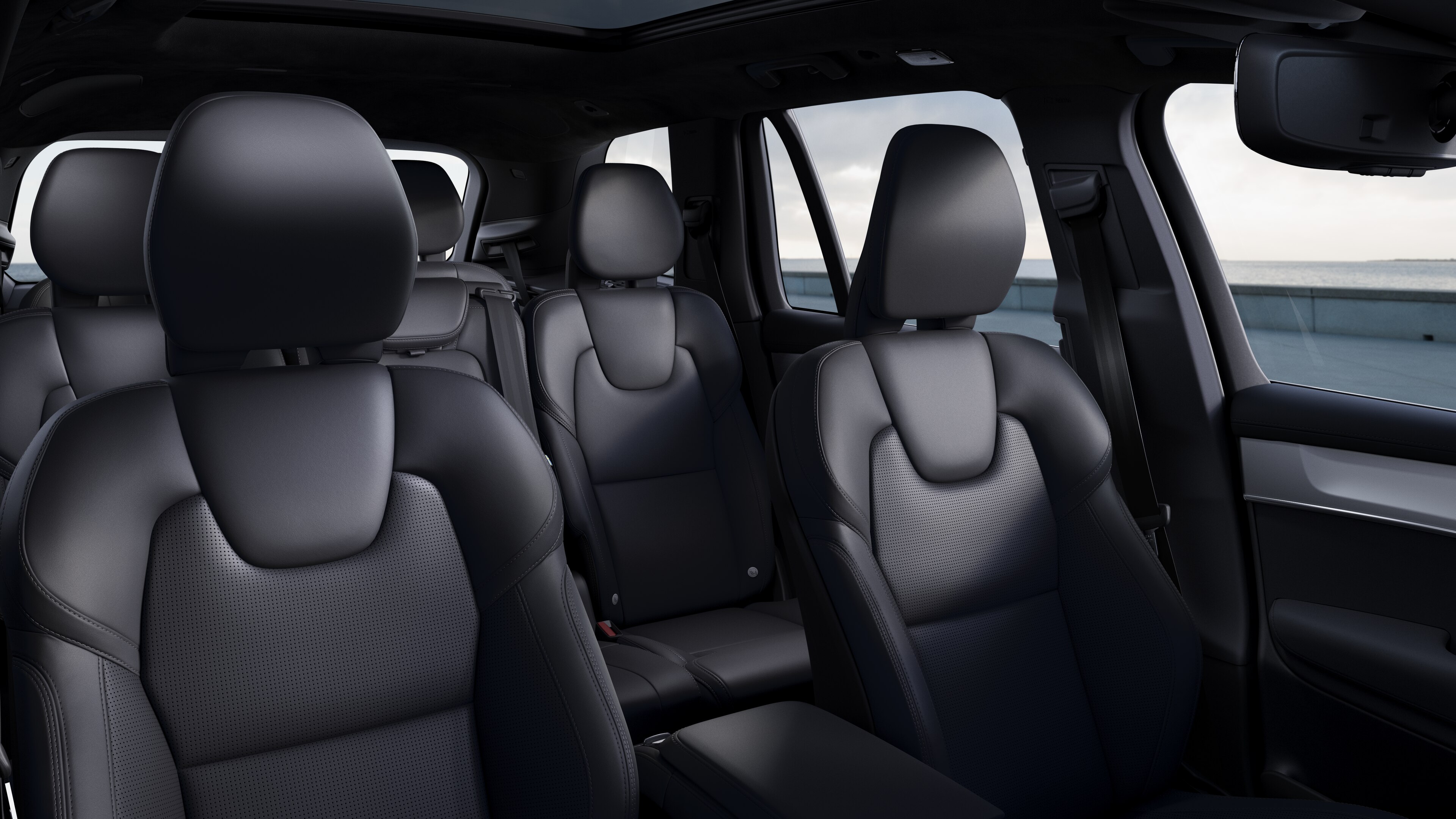 Het interieur van een Volvo met de passagiersstoelen voor- en achterin, het stuur, het dashboard en de middenconsole tegen een effen studioachtergrond.
