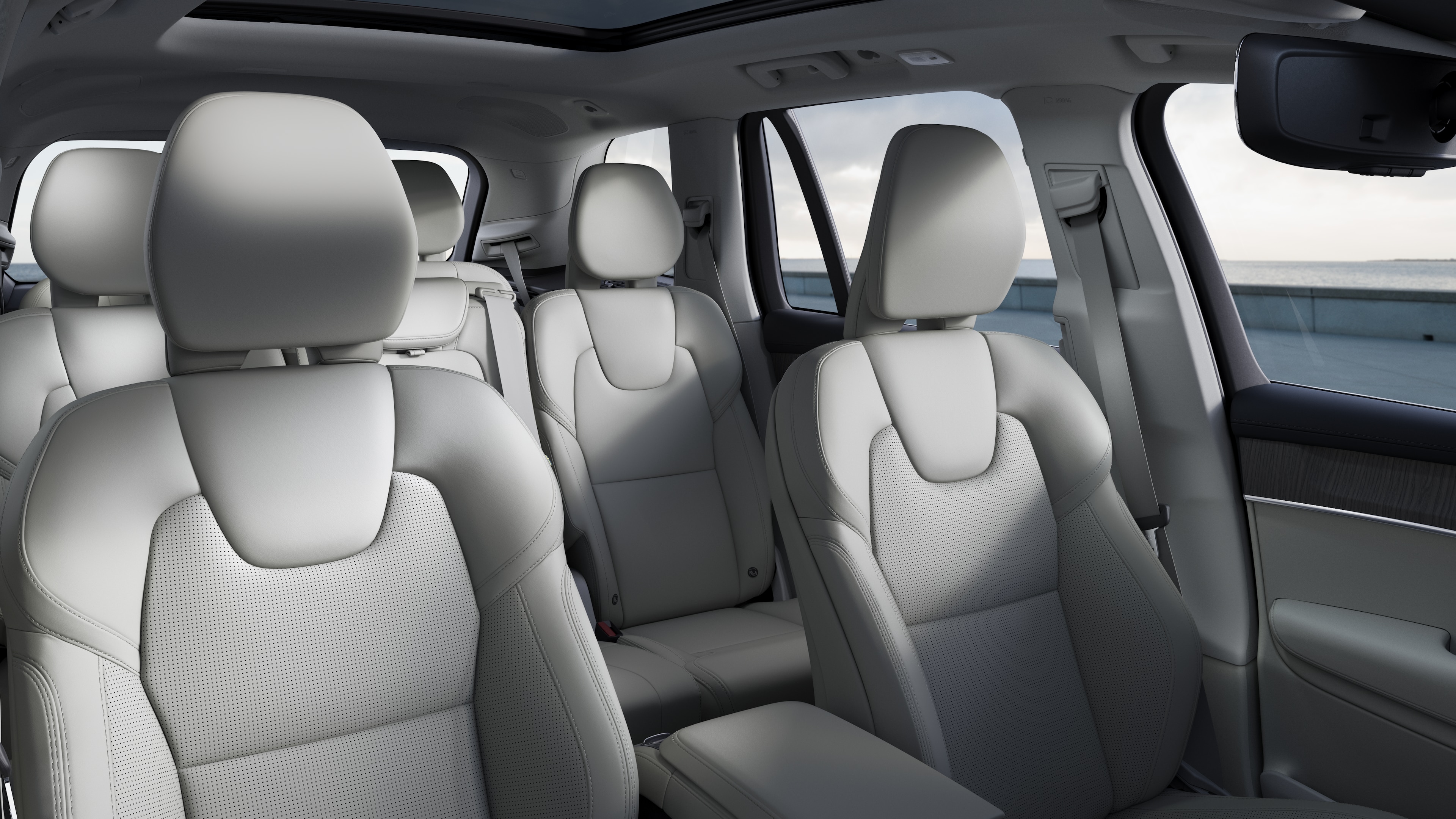 Interior del vehículo Volvo que muestra los asientos delanteros y traseros de los pasajeros, el volante, el salpicadero y la consola central sobre un fondo de estudio liso.