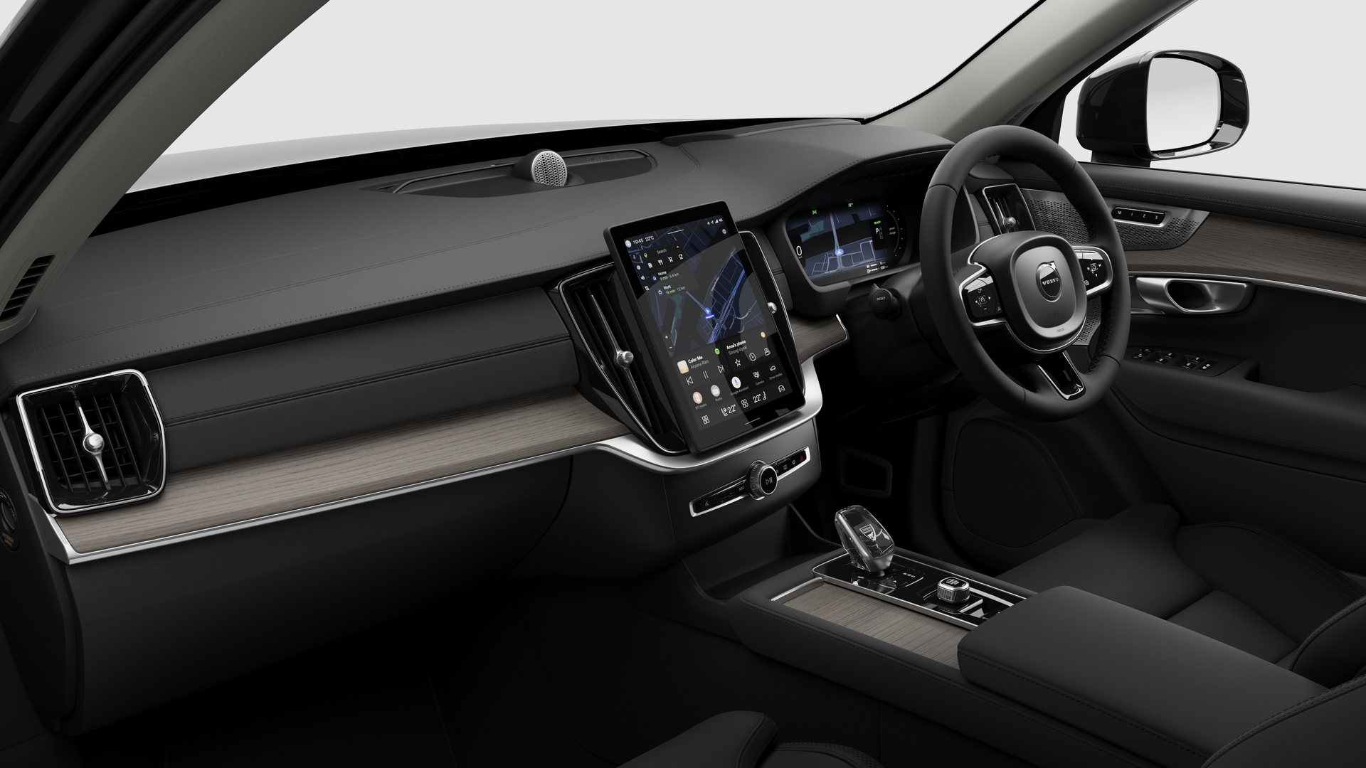 Interior view of a Volvo car showing the dashboard, steering wheel, center console, and digital display screen in a plain studio background.