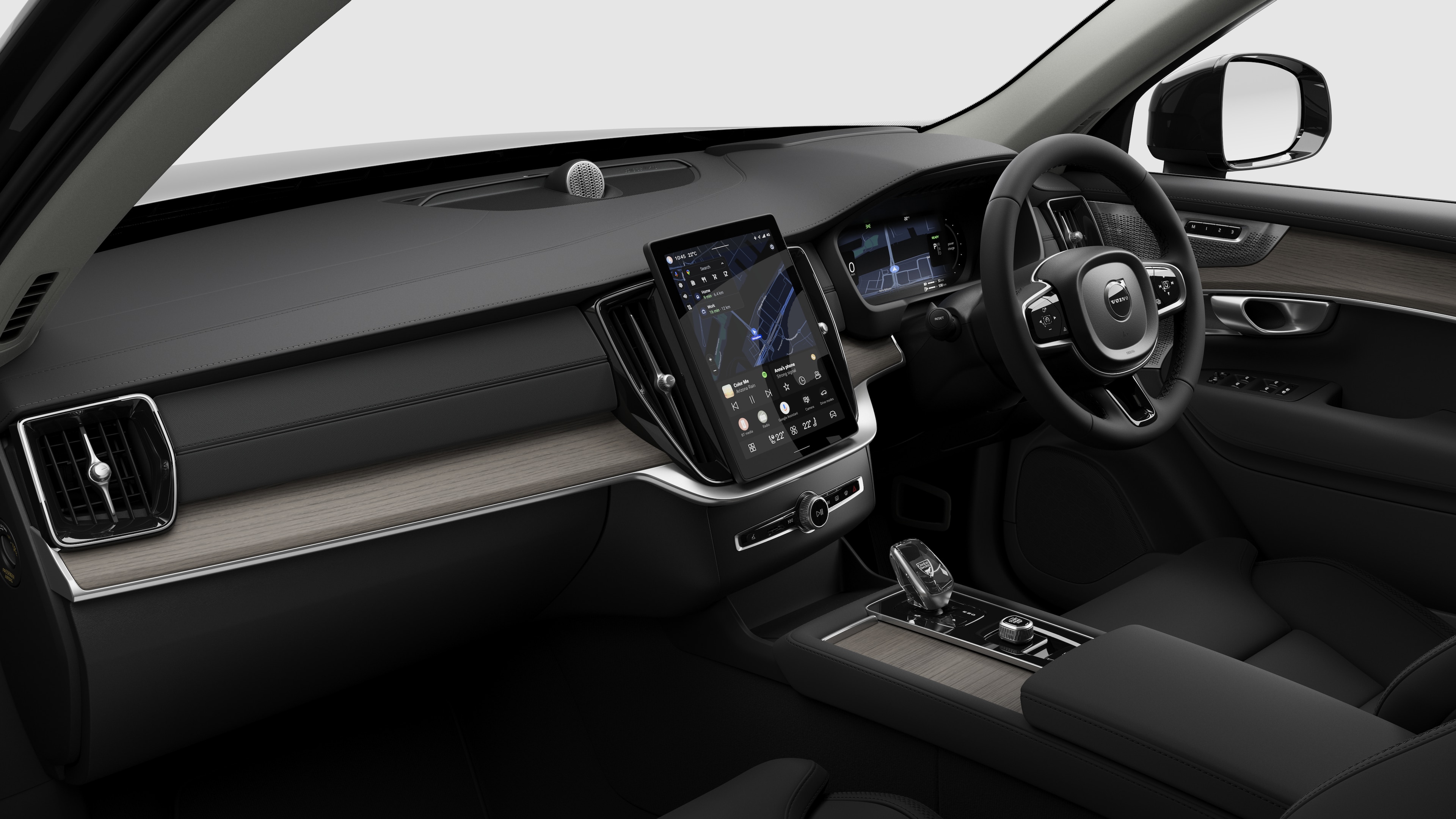 Interior view of a Volvo car showing the dashboard, steering wheel, center console, and digital display screen in a plain studio background.