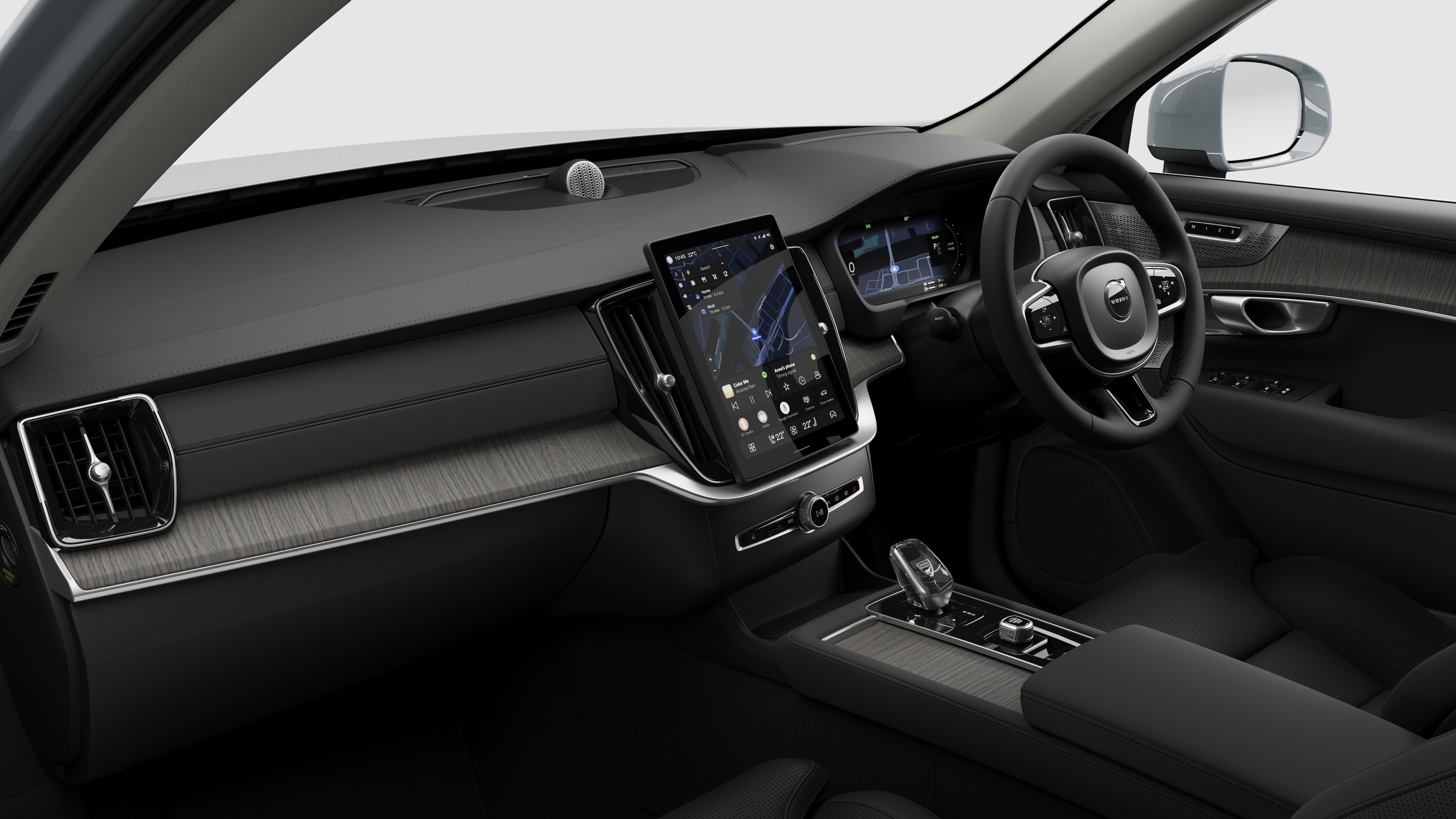 Interior view of a Volvo car showing the dashboard, steering wheel, center console, and digital display screen in a plain studio background.