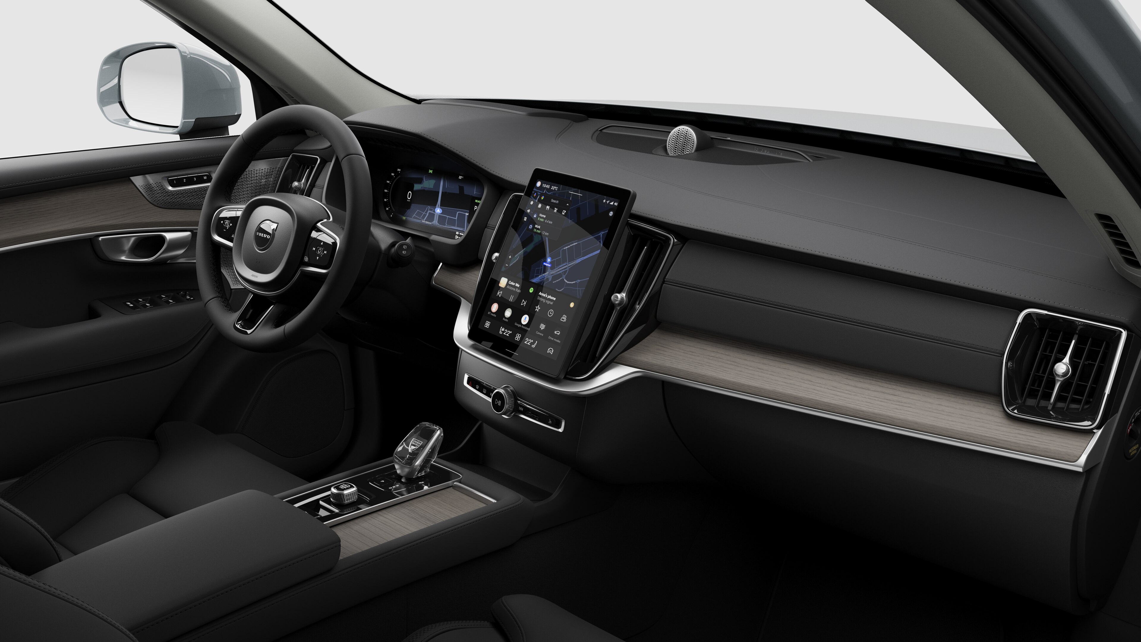 Interior view of a Volvo car showing the dashboard, steering wheel, center console, and digital display screen in a plain studio background.