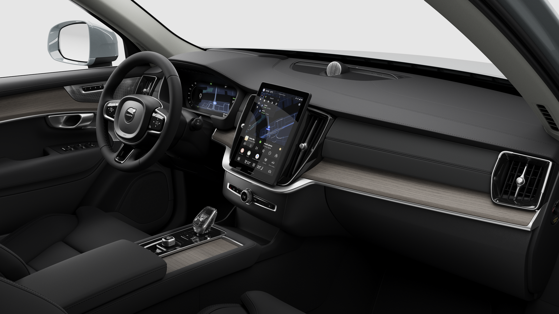 Interior view of a Volvo car showing the dashboard, steering wheel, center console, and digital display screen in a plain studio background.