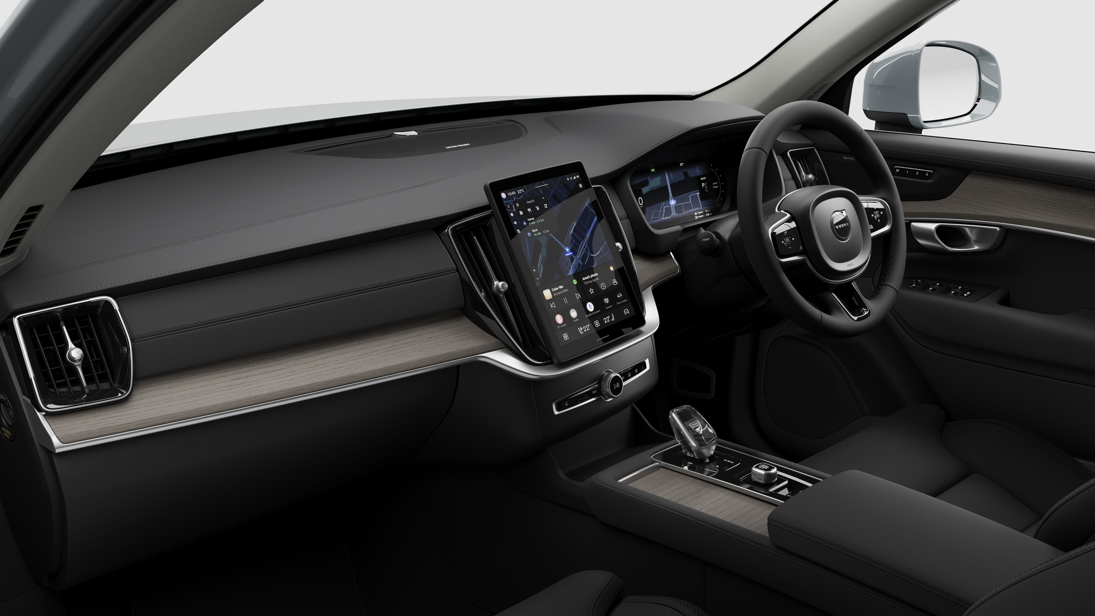 Interior view of a Volvo car showing the dashboard, steering wheel, center console, and digital display screen in a plain studio background.