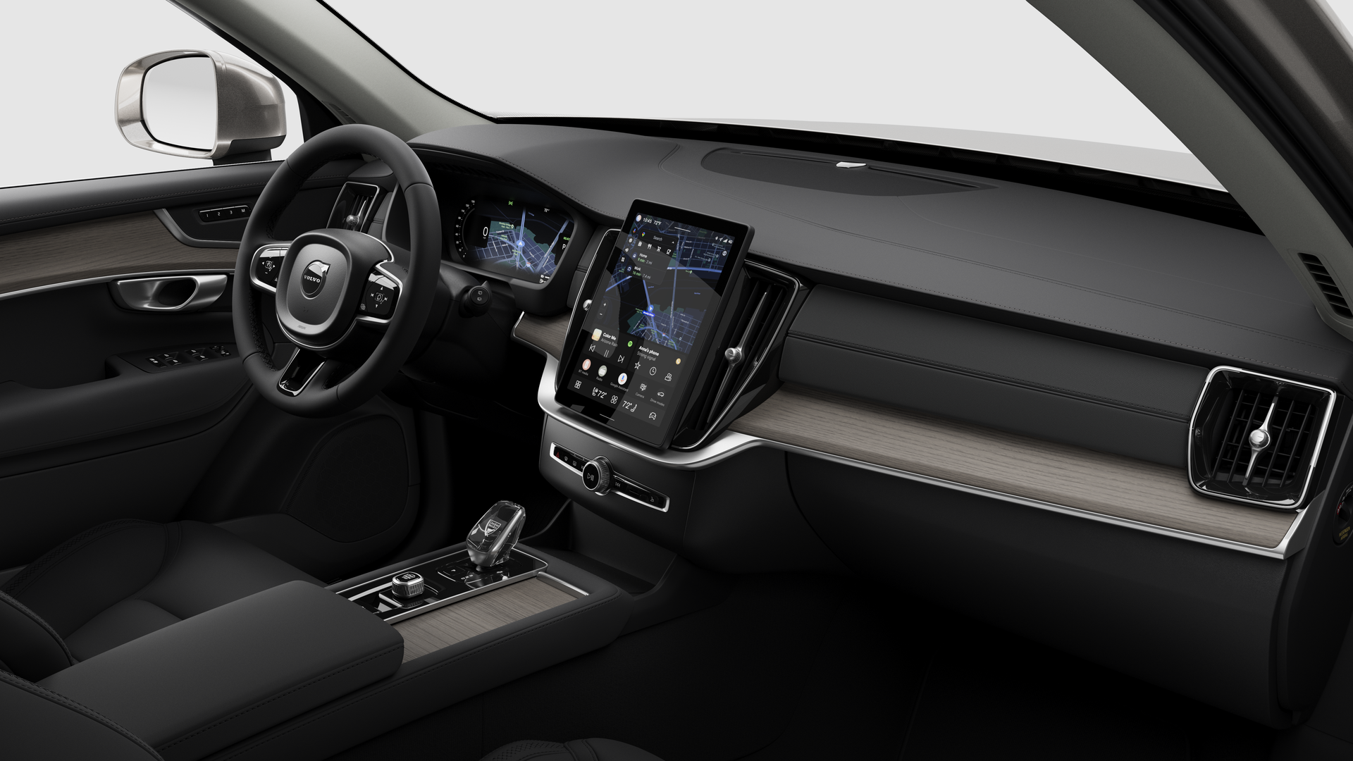 Interior view of a Volvo car showing the dashboard, steering wheel, center console, and digital display screen in a plain studio background.