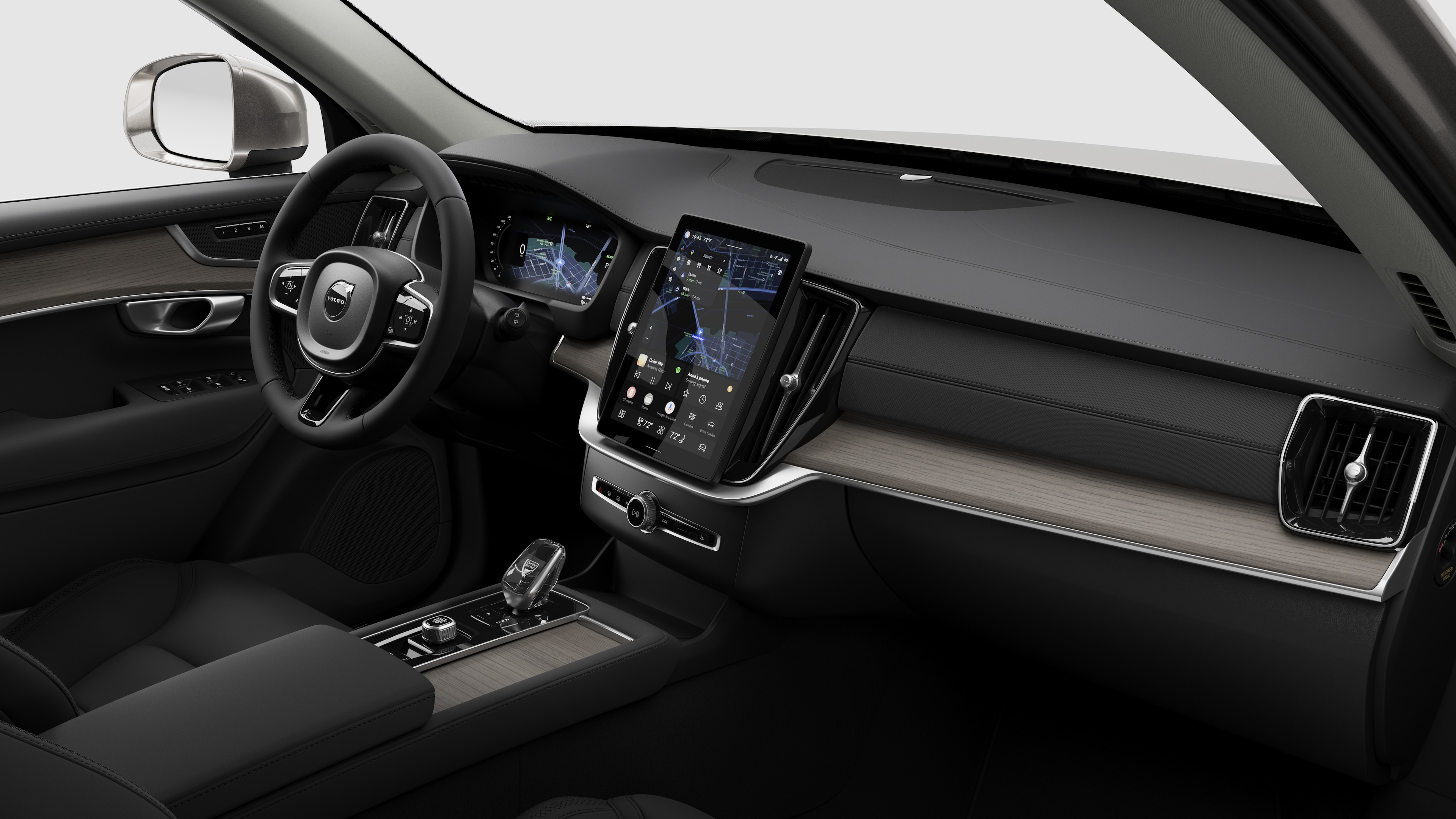 Interior view of a Volvo car showing the dashboard, steering wheel, center console, and digital display screen in a plain studio background.