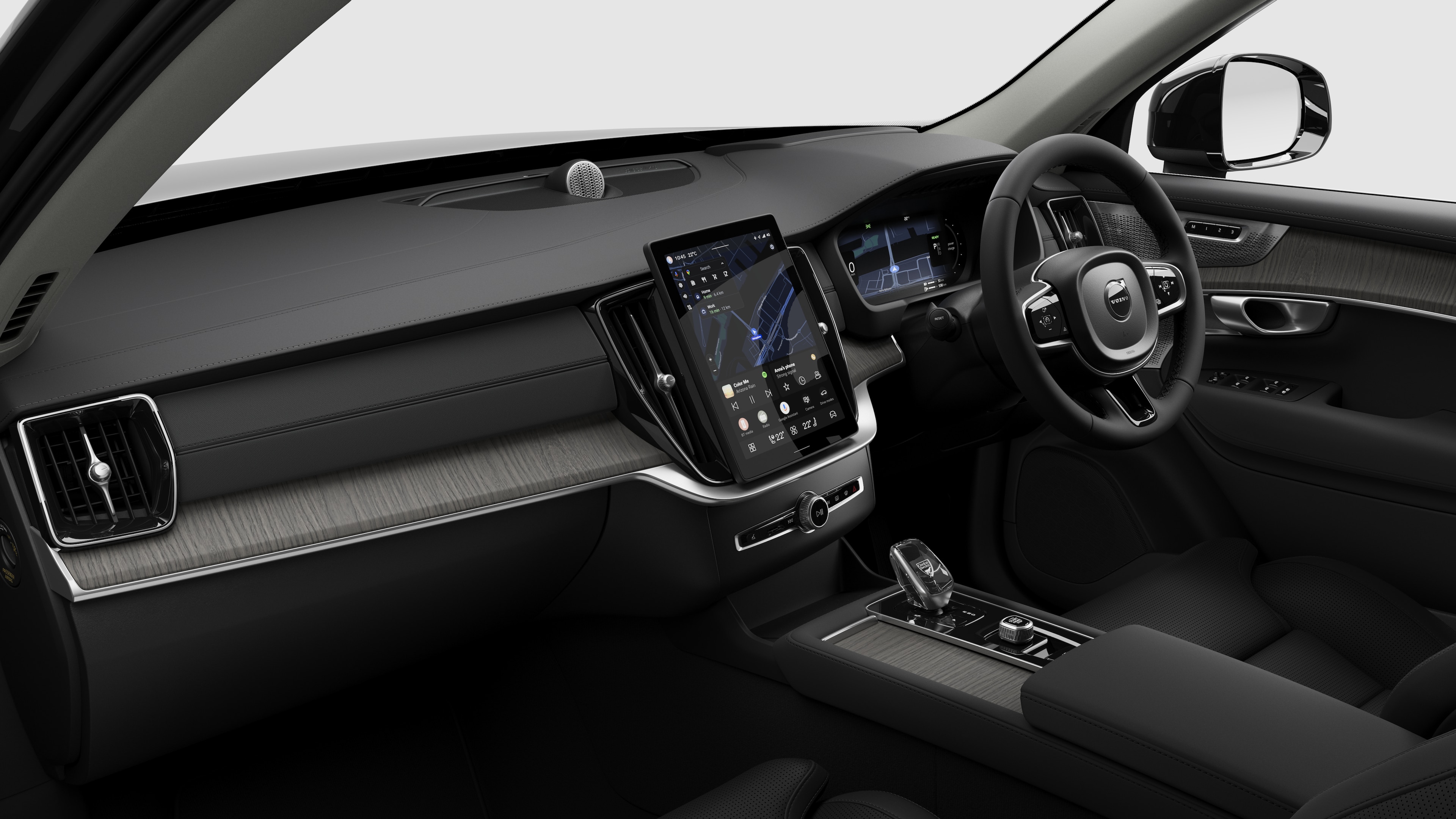 Interior view of a Volvo car showing the dashboard, steering wheel, center console, and digital display screen in a plain studio background.