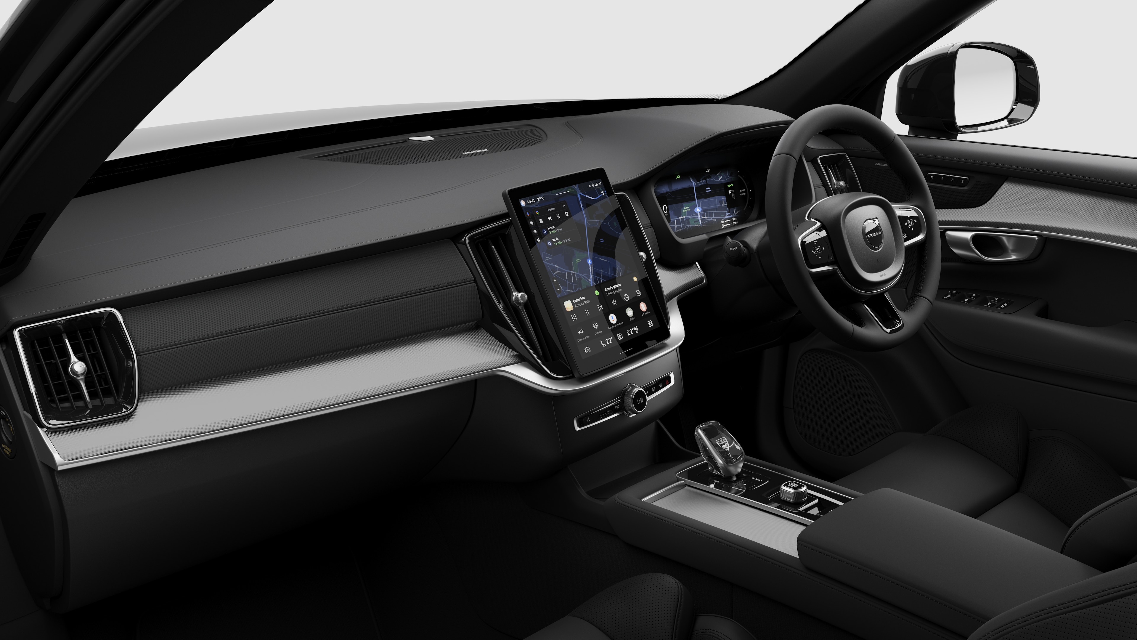 Interior view of a Volvo car showing the dashboard, steering wheel, centre console, and digital display screen in a plain studio background.