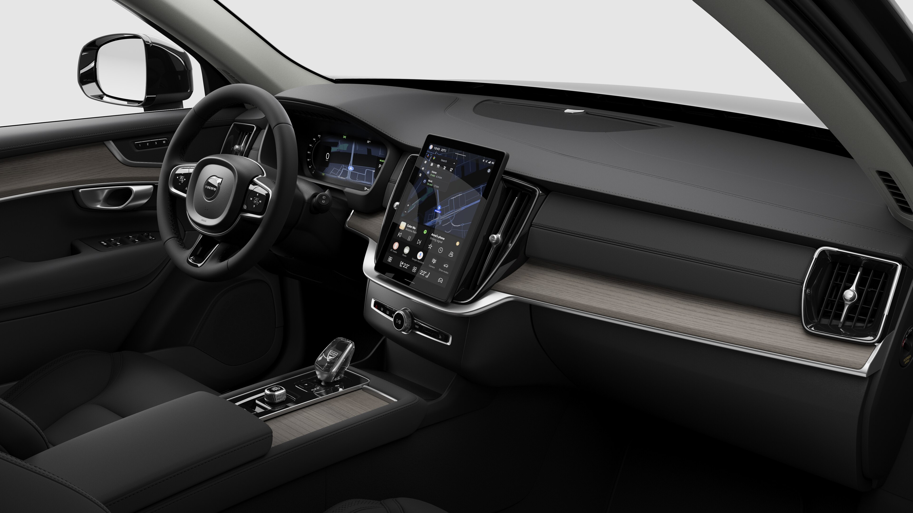 Interior view of a Volvo car showing the dashboard, steering wheel, center console, and digital display screen in a plain studio background.