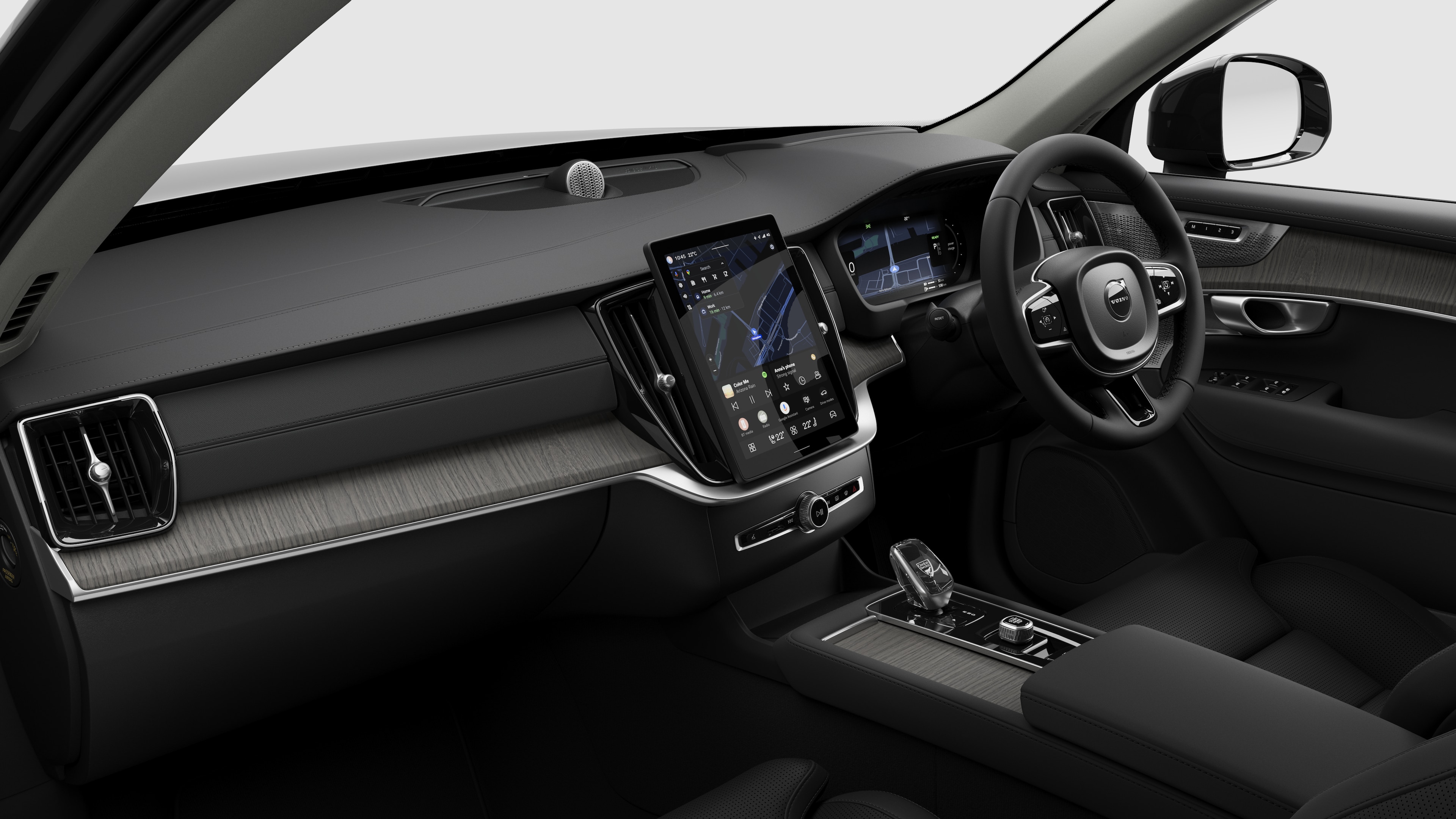 Interior view of a Volvo car showing the dashboard, steering wheel, center console, and digital display screen in a plain studio background.