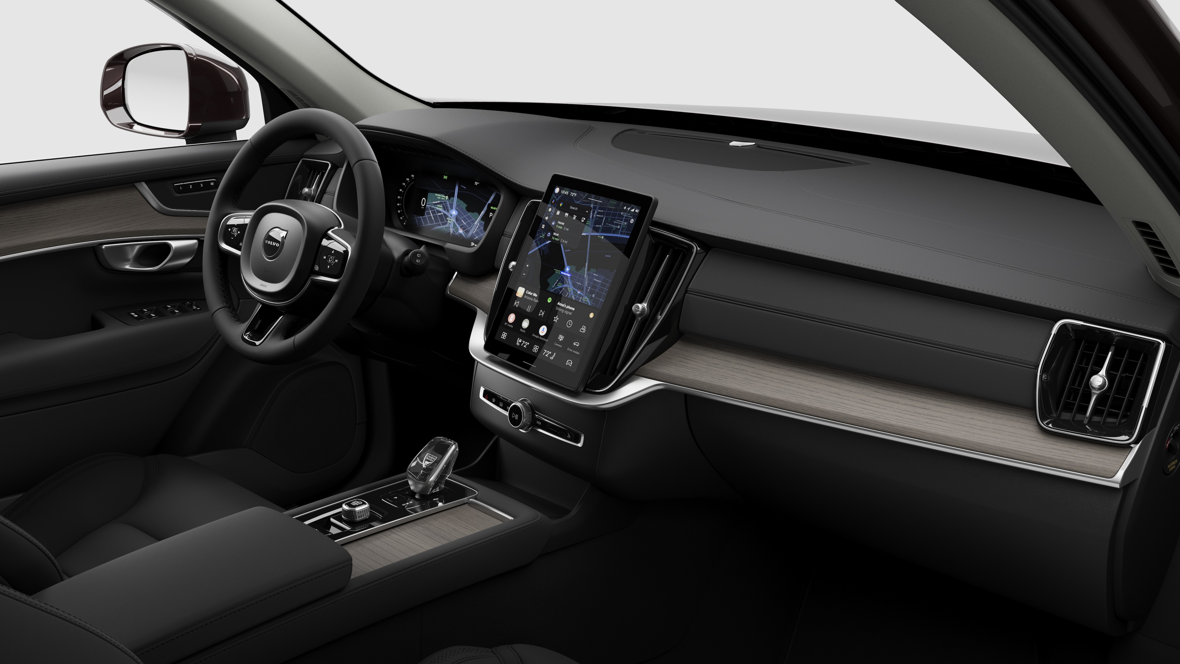 Interior view of a Volvo car showing the dashboard, steering wheel, center console, and digital display screen in a plain studio background.