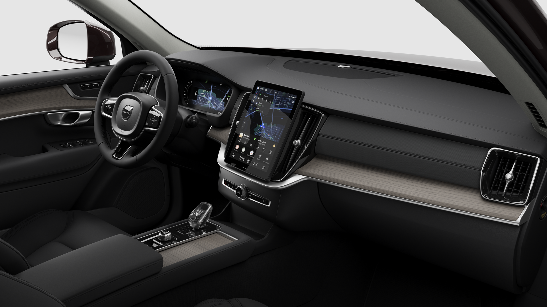 Interior view of a Volvo car showing the dashboard, steering wheel, center console, and digital display screen in a plain studio background.