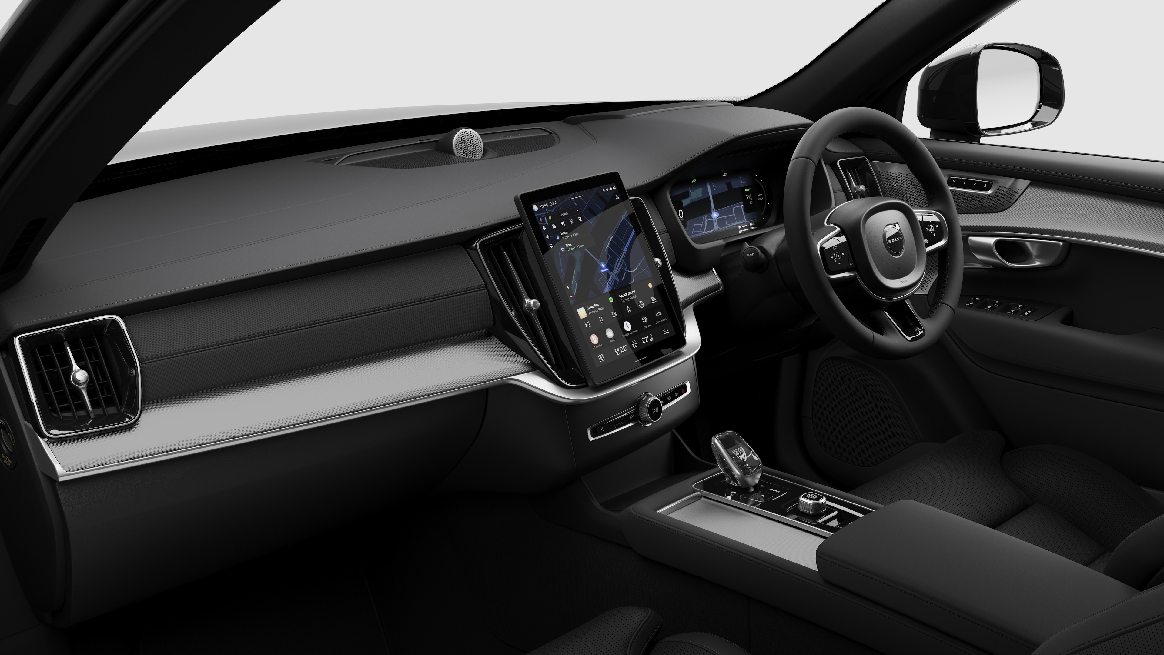 Interior view of a Volvo car showing the dashboard, steering wheel, center console, and digital display screen in a plain studio background.