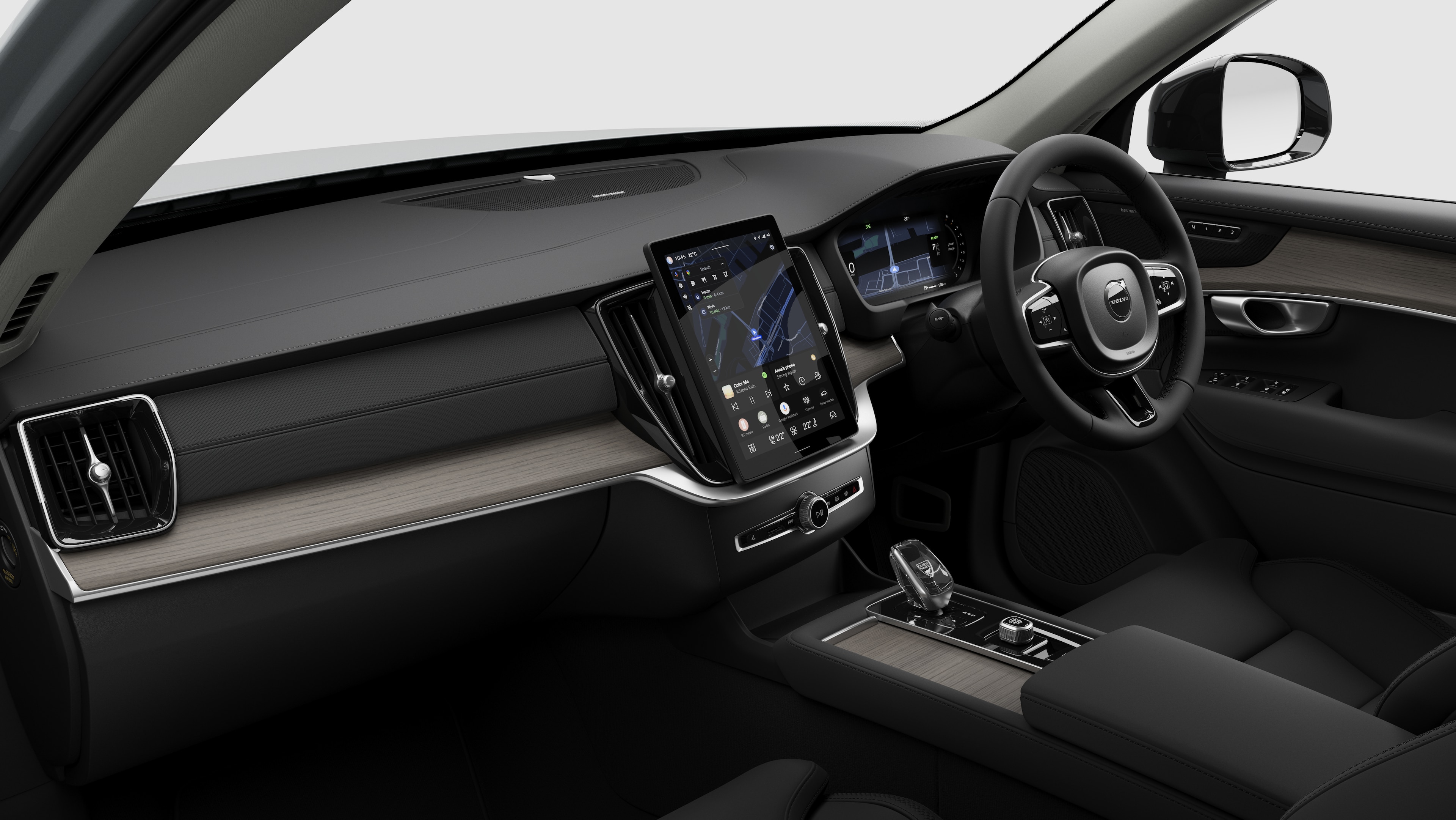 Interior view of a Volvo car showing the dashboard, steering wheel, center console, and digital display screen in a plain studio background.