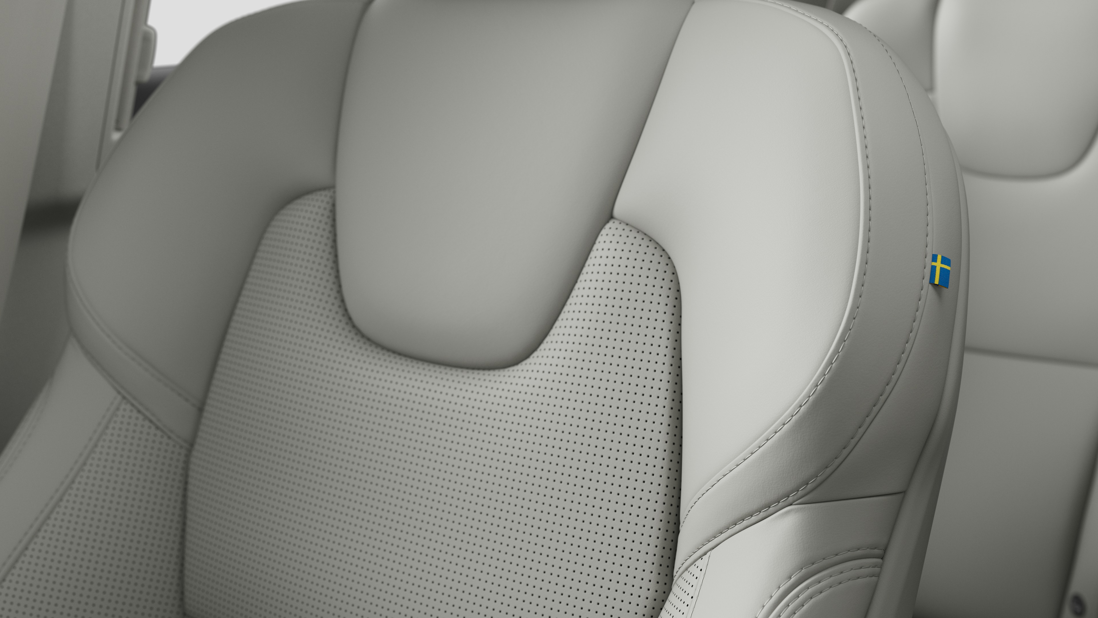 Primer plano del detalle del asiento interior del vehículo Volvo que muestra costuras y una pequeña etiqueta con la bandera sueca.