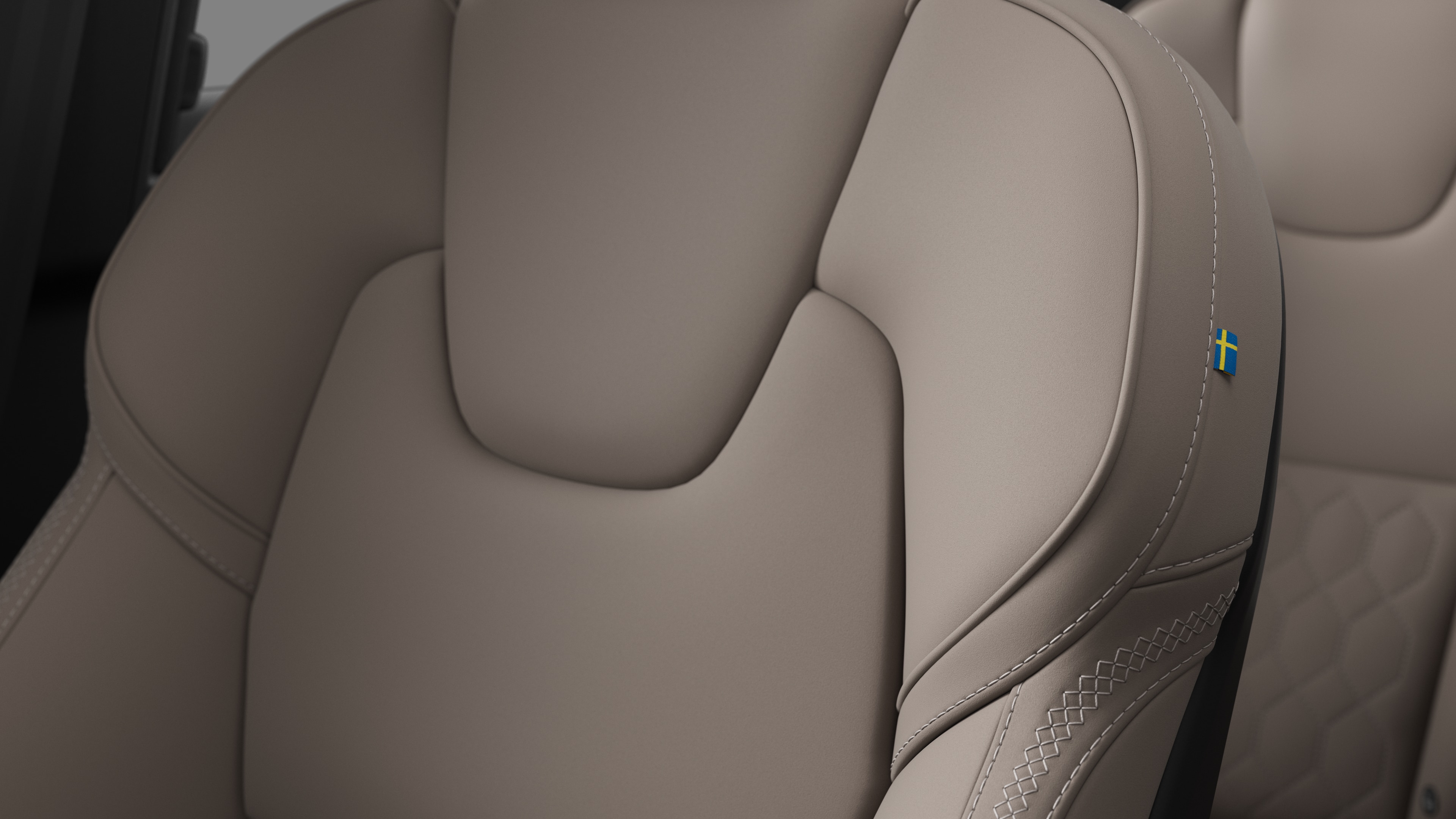 Close-up of Volvo car interior seat detail showing stitching and a small Swedish flag tag.