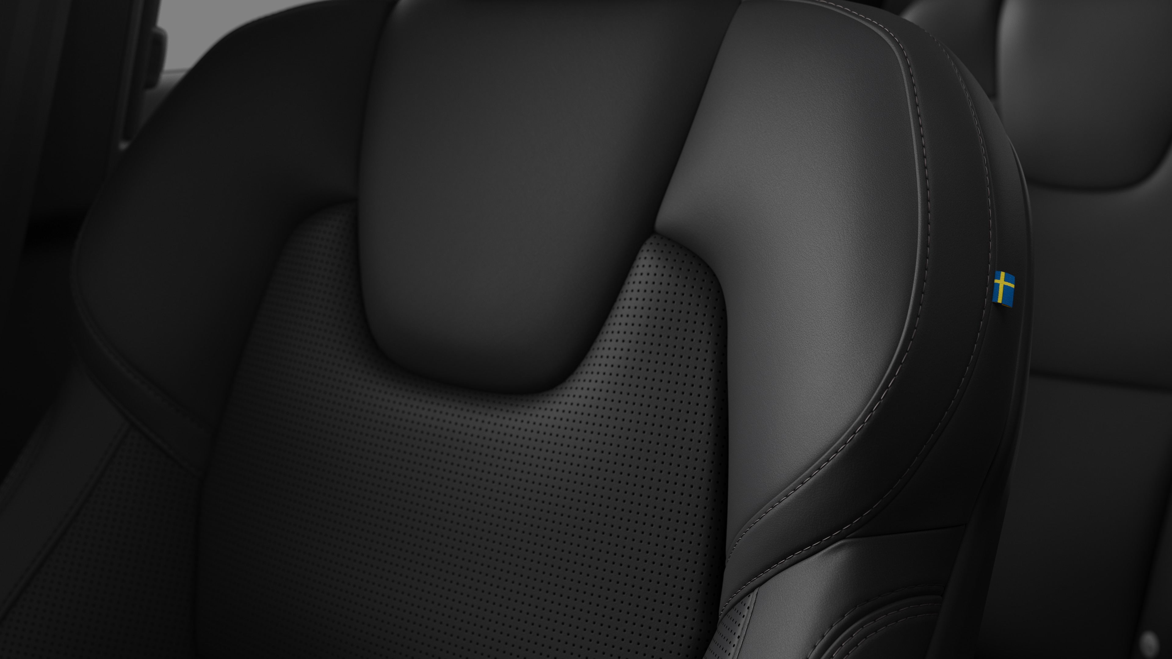 Close-up of Volvo car interior seat detail showing stitching and a small Swedish flag tag.