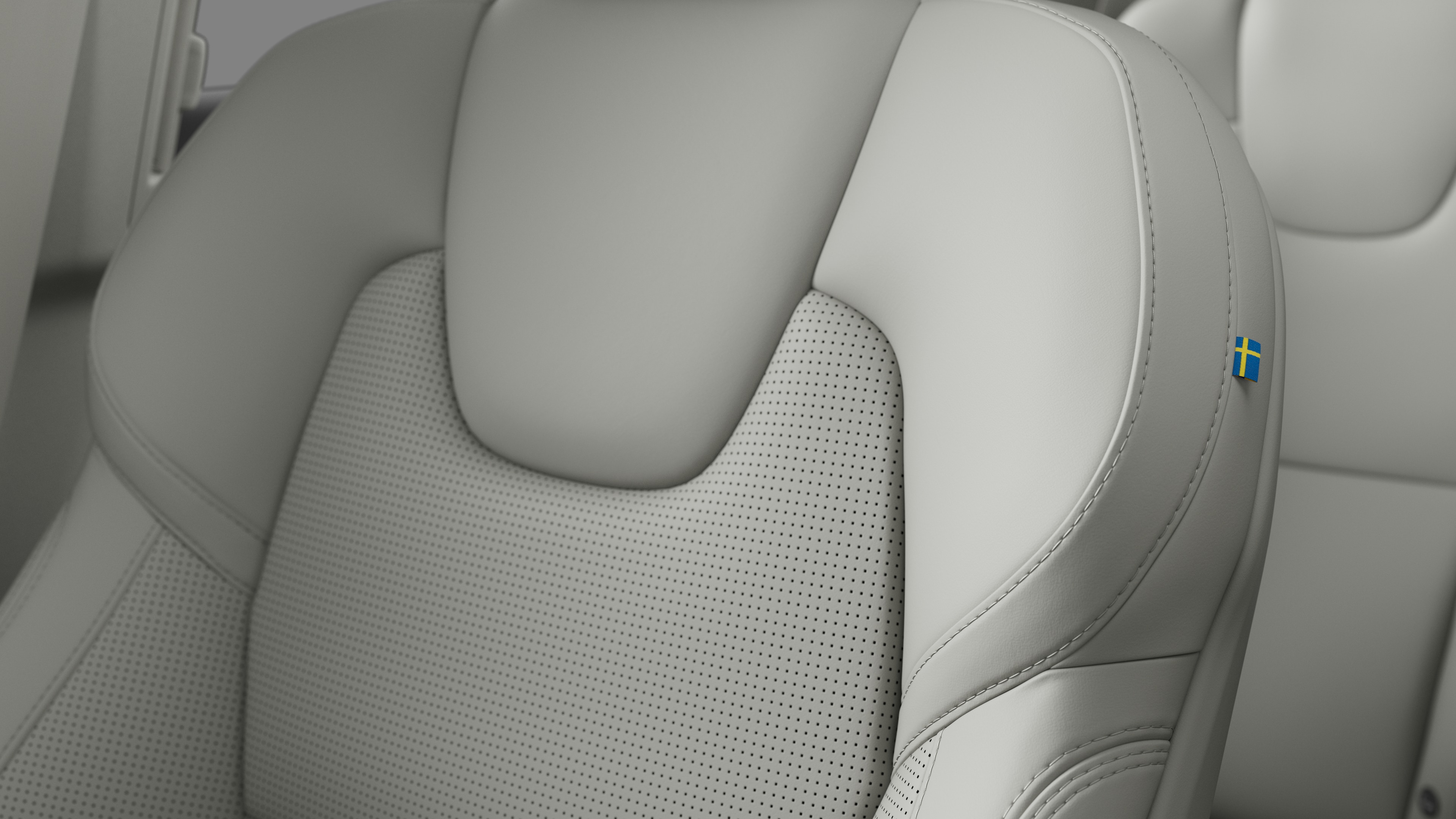 Närbild av Volvo Cars interiör, sätesdetalj som visar sömmar och en liten svensk flagga.
