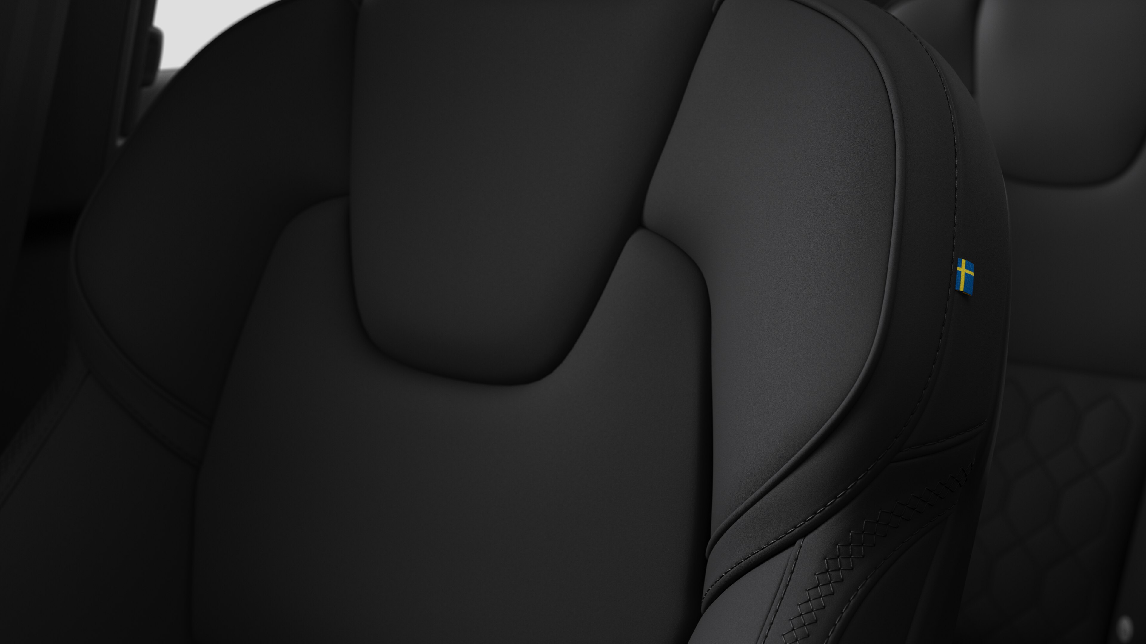 Nærbilde av Volvos interiørsetedetaljer med sømmer og et lite svensk flaggmerke.