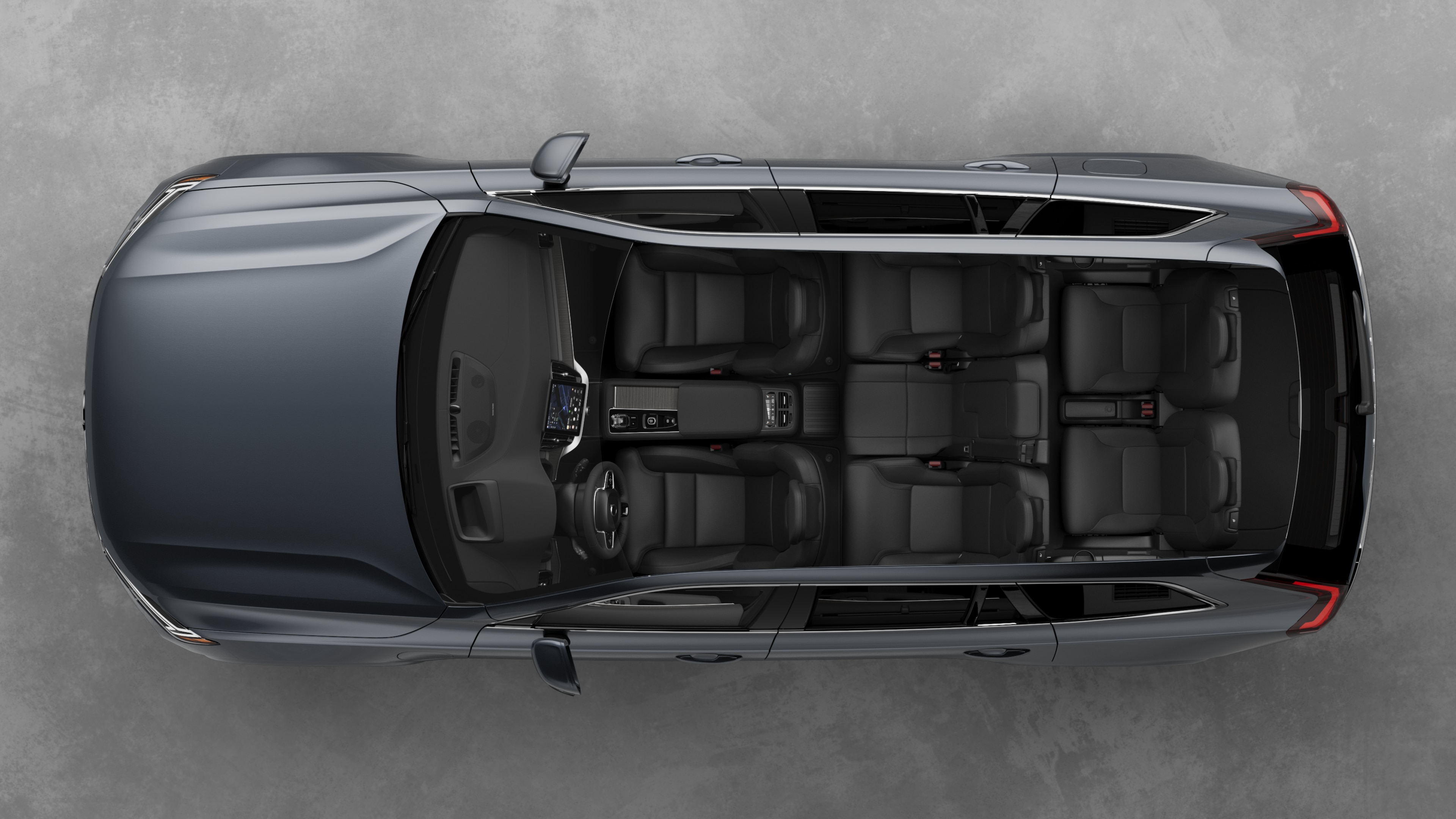Top view of Volvo car interior, showing two rows of seats, dashboard, and center console, set against a plain studio background.