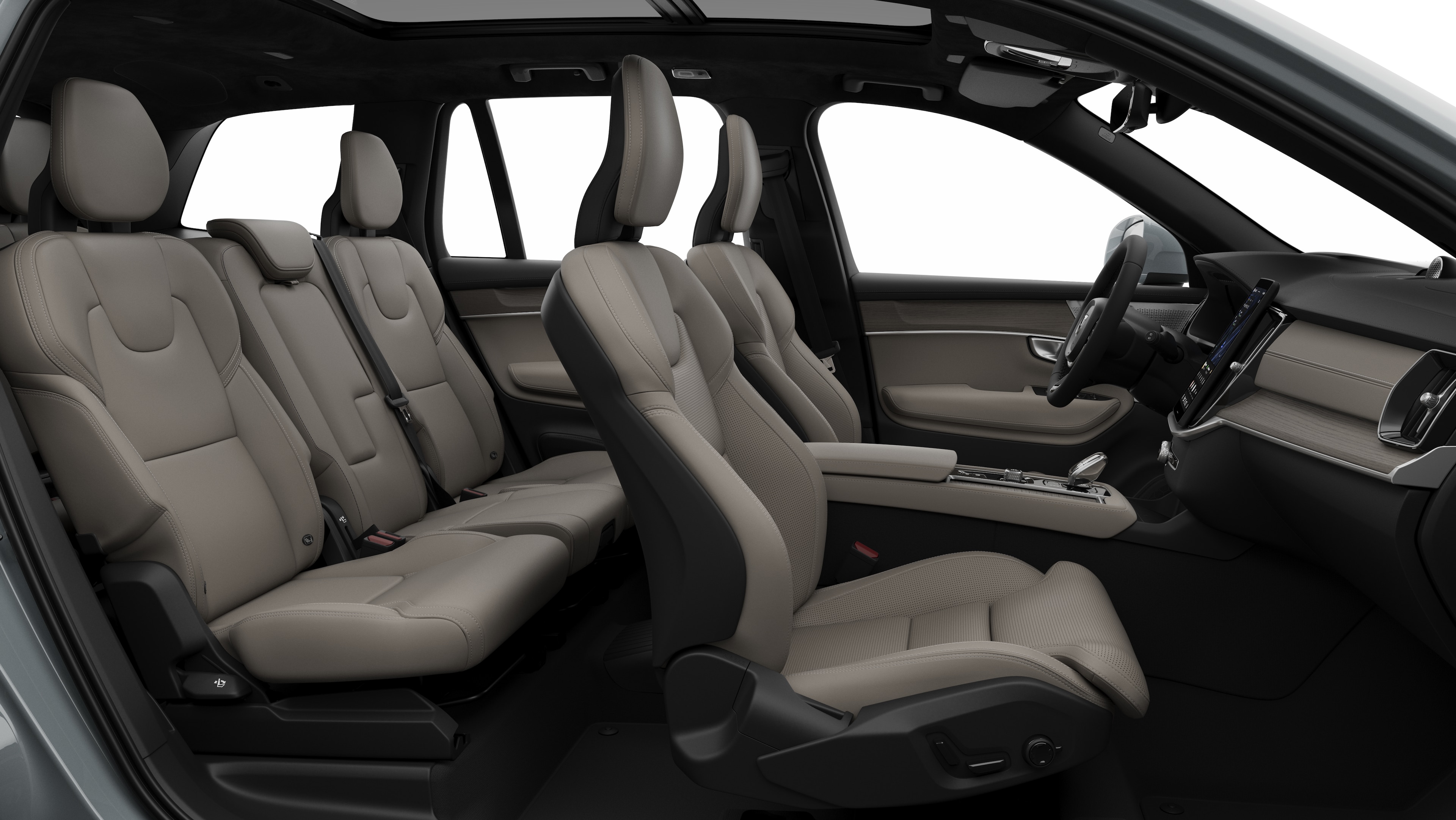 Zijaanzicht van het interieur van een Volvo met de voorstoelen, de passagiersstoelen achterin, het stuur, het dashboard en de middenconsole, tegen een effen studioachtergrond.