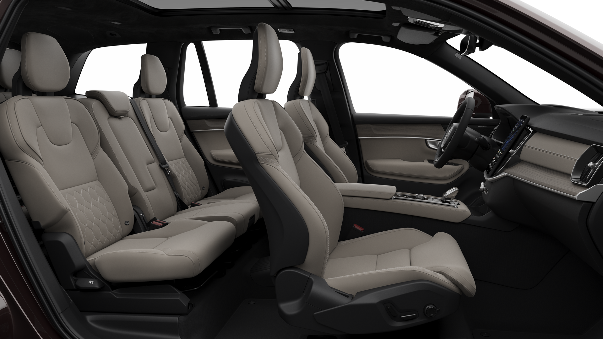 Vue latérale de l’intérieur d’une Volvo montrant les sièges avant, les sièges passager arrière, le volant, le tableau de bord et la console centrale, sur fond de studio.