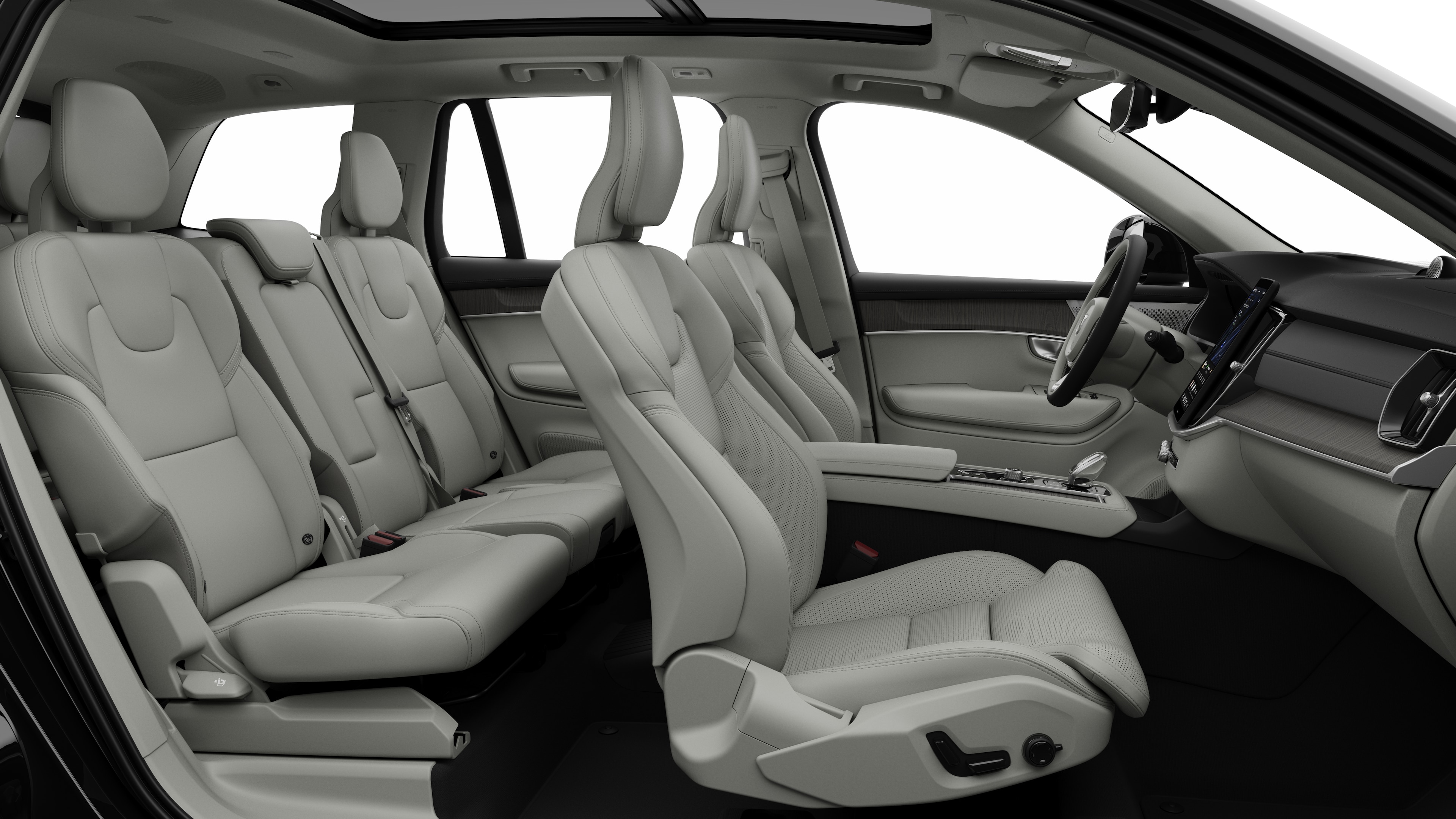 Vista lateral do interior do carro Volvo mostrando os bancos dianteiros, traseiros do passageiro, volante, painel de instrumentos e console central, contra um plano de fundo de estúdio simples.