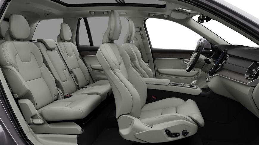 Volvo car interior side view showcasing front seats, rear passenger seats, steering wheel, dashboard, and center console, set against plain studio background.
