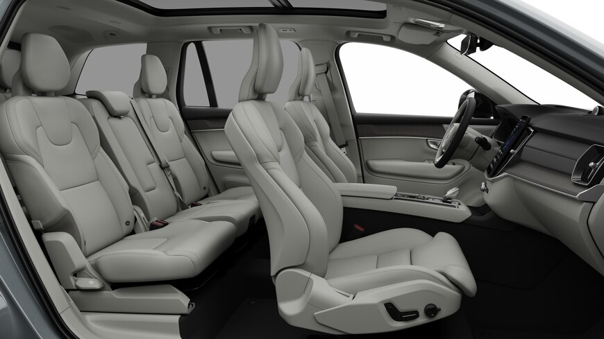 Pohled zboku do interiéru vozu Volvo s předními sedadly, zadními sedadly spolujezdce, volantem, palubní deskou a středovou konzolou na jednoduchém pozadí studia.