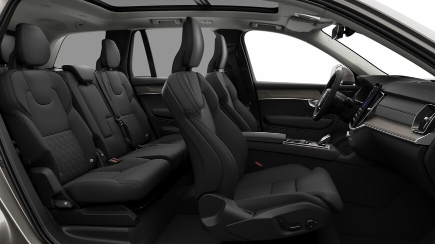 Seitenansicht des Innenraums eines Volvo mit Vordersitzen, Beifahrersitzen, Lenkrad, Armaturenbrett und Mittelkonsole vor einem schlichten Studiohintergrund.
