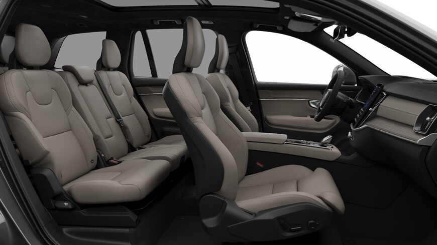 Vue latérale de l’intérieur d’une Volvo montrant les sièges avant, les sièges passager arrière, le volant, le tableau de bord et la console centrale, sur fond de studio.